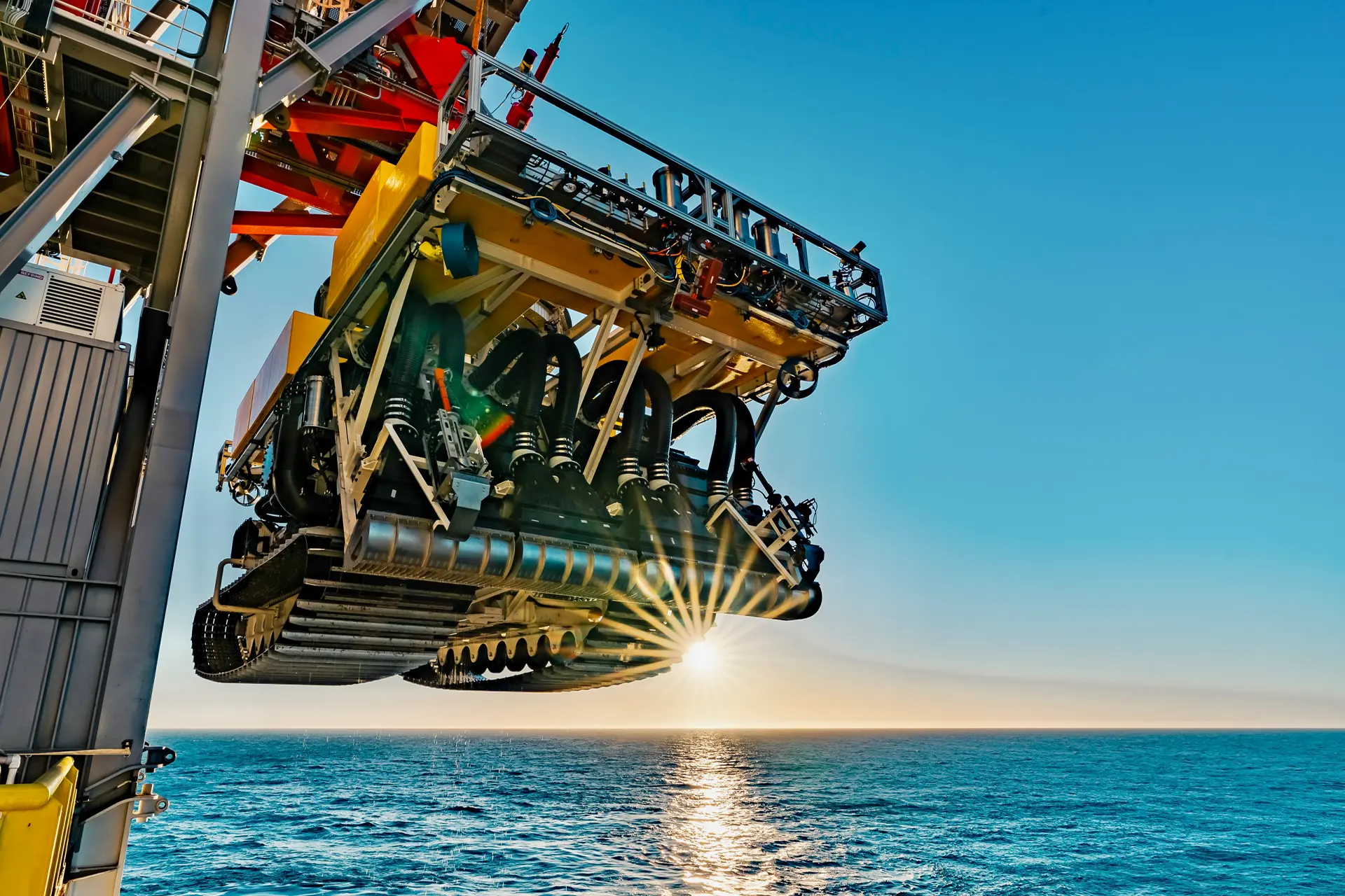 Underwater mining vessel hanging from a crane over the ocean