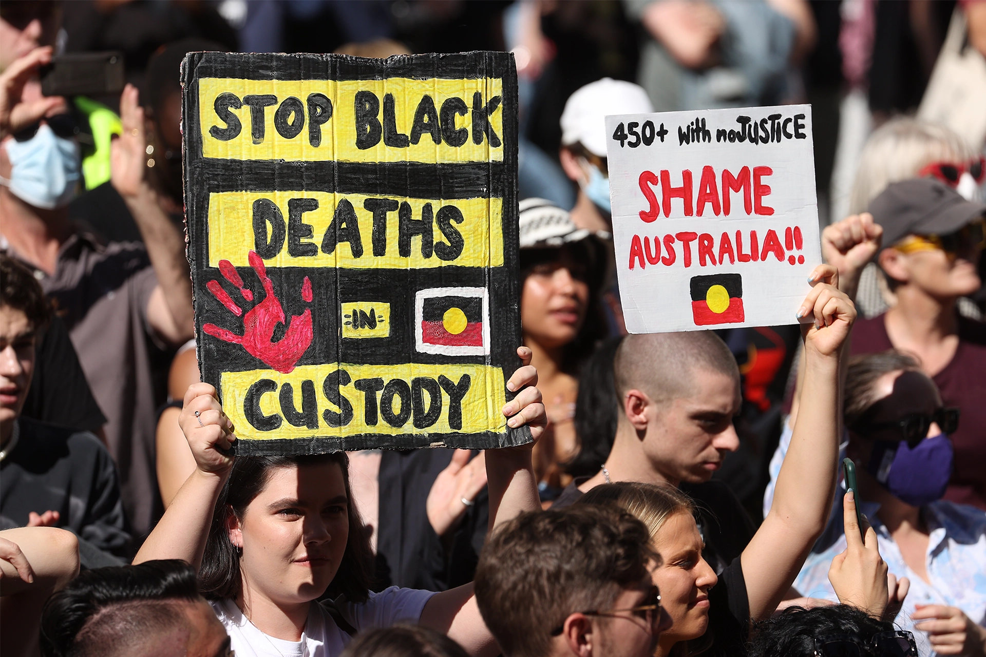 Crowds of people holding signs protesting Aboriginal deaths in custody