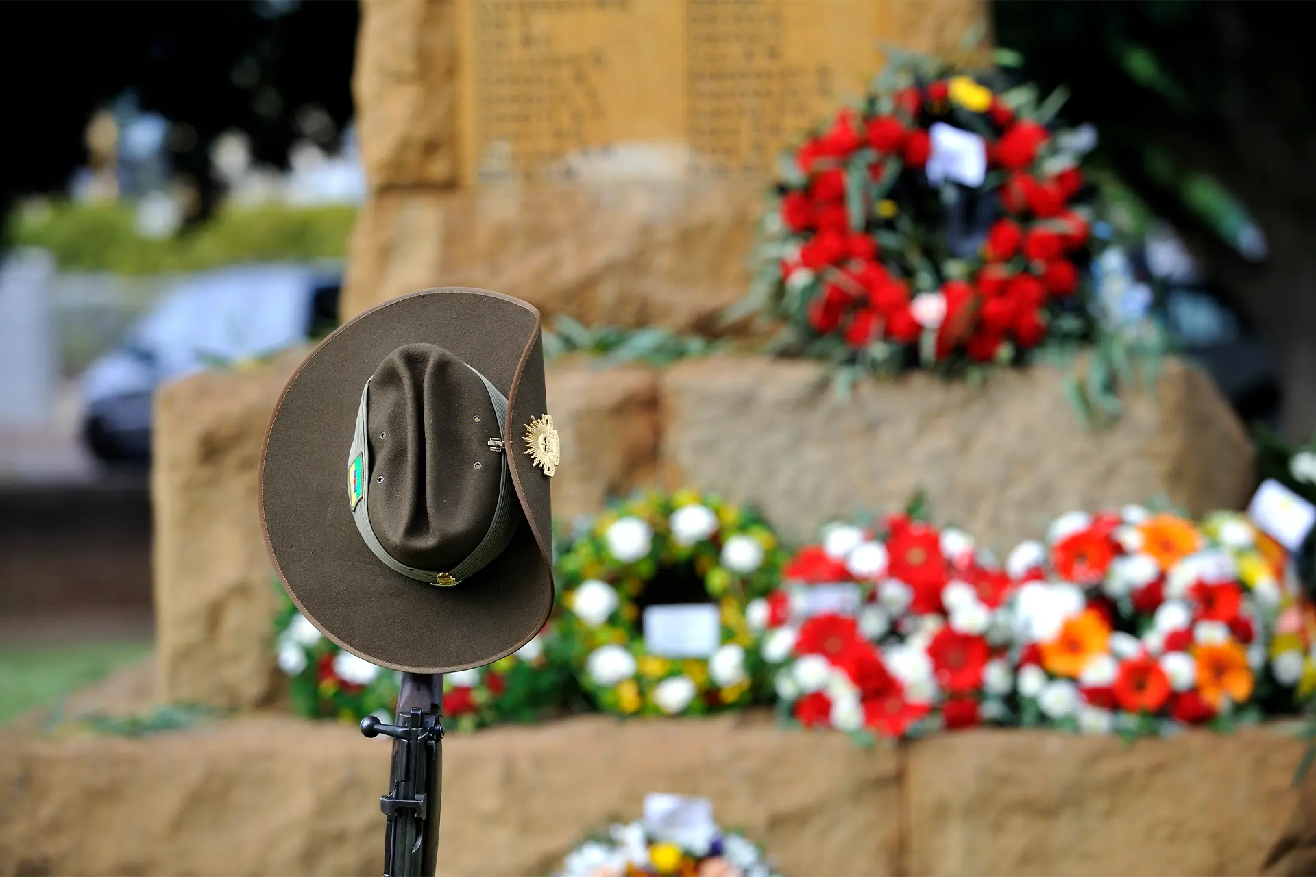 An Anzac hat on a rifle in front of a memorial