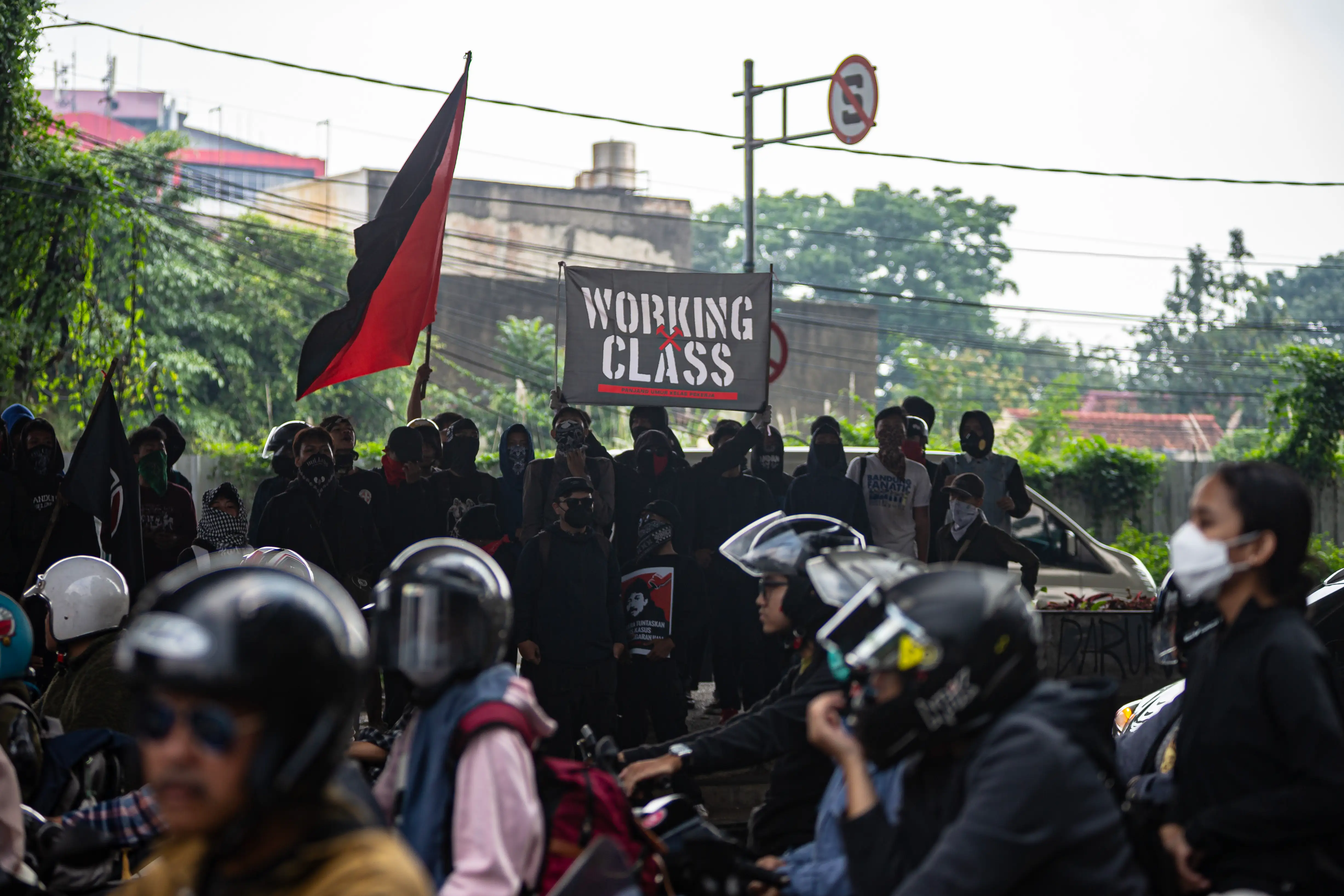 A protestor holds a banner in the middle of the road during a rally to commemorate May Day