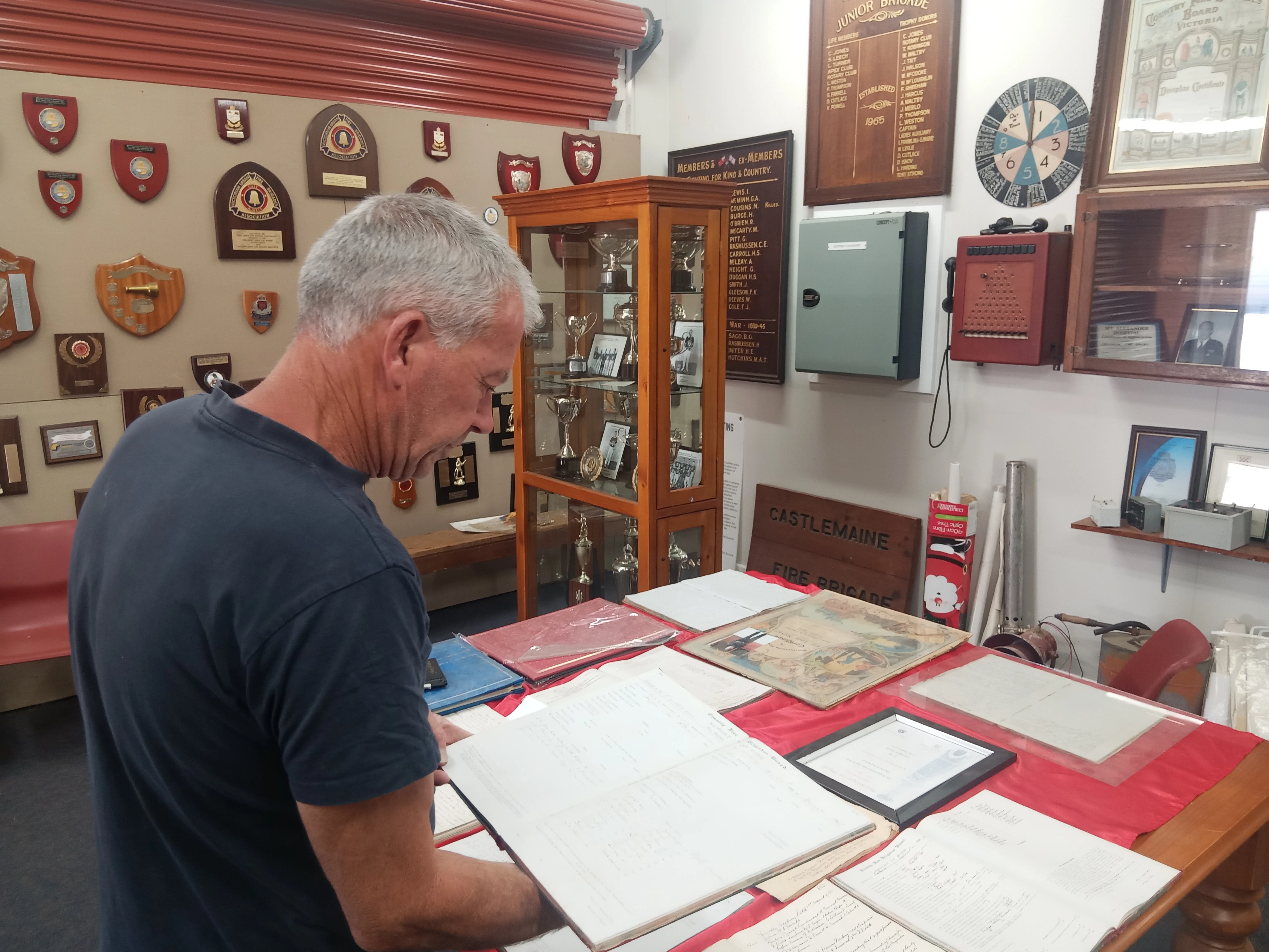 A man holds one of the old Fire Books on display in the Castlemaine museum and the walls are covered in memorabilia