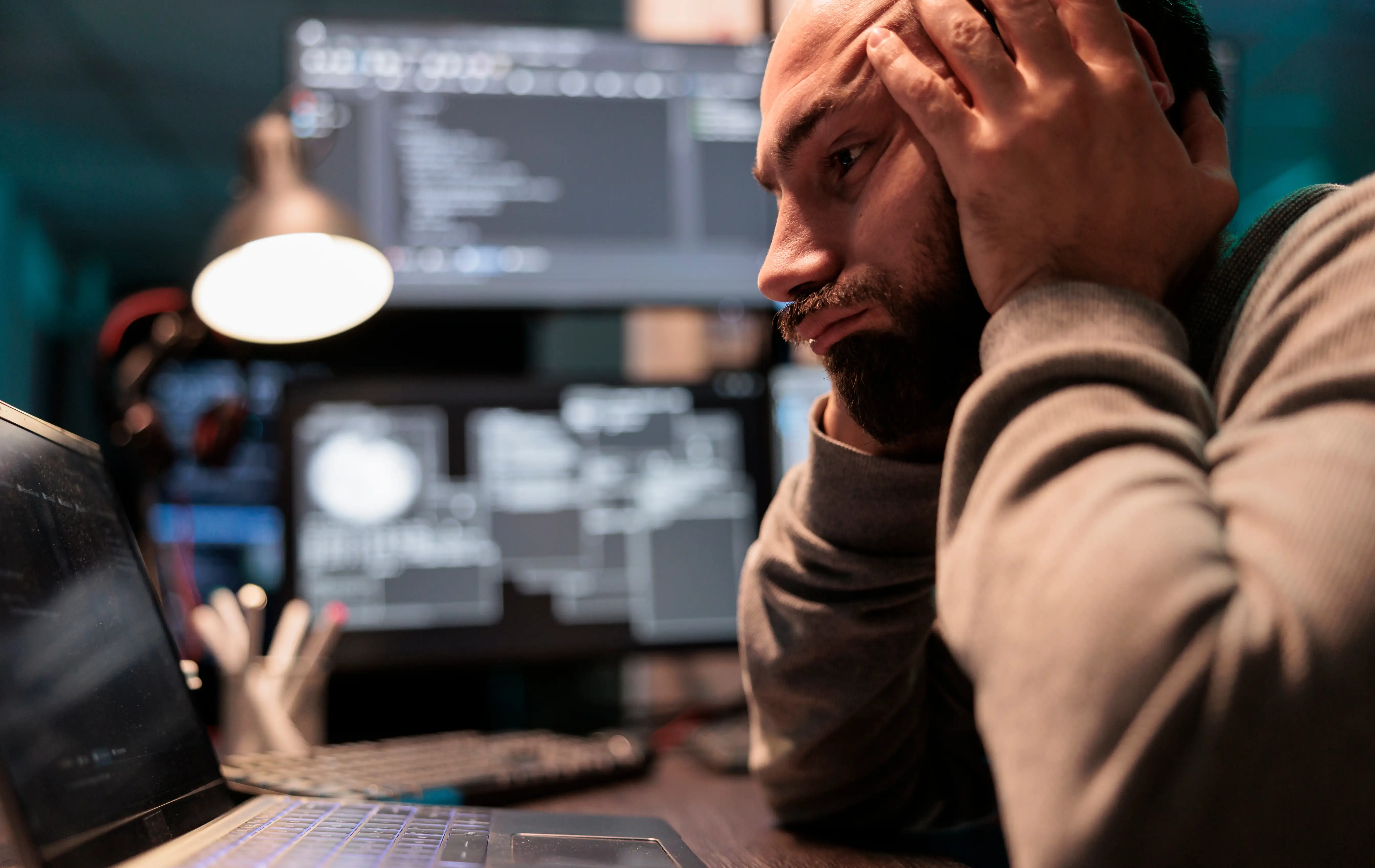 A stressed man in front of an AI prompt screen on a laptop