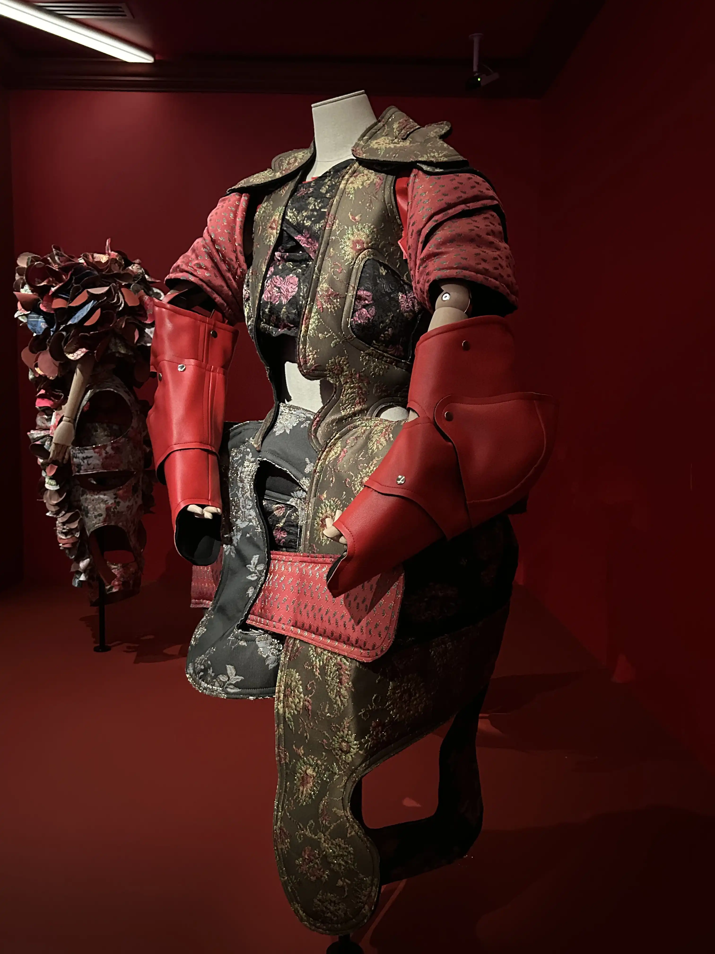 A Kawakubo designed garment with various clashing floral patterns and wide padded arms on display in the National Gallery of Victoria