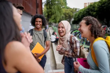 A group of university students speaking and smiling on campus