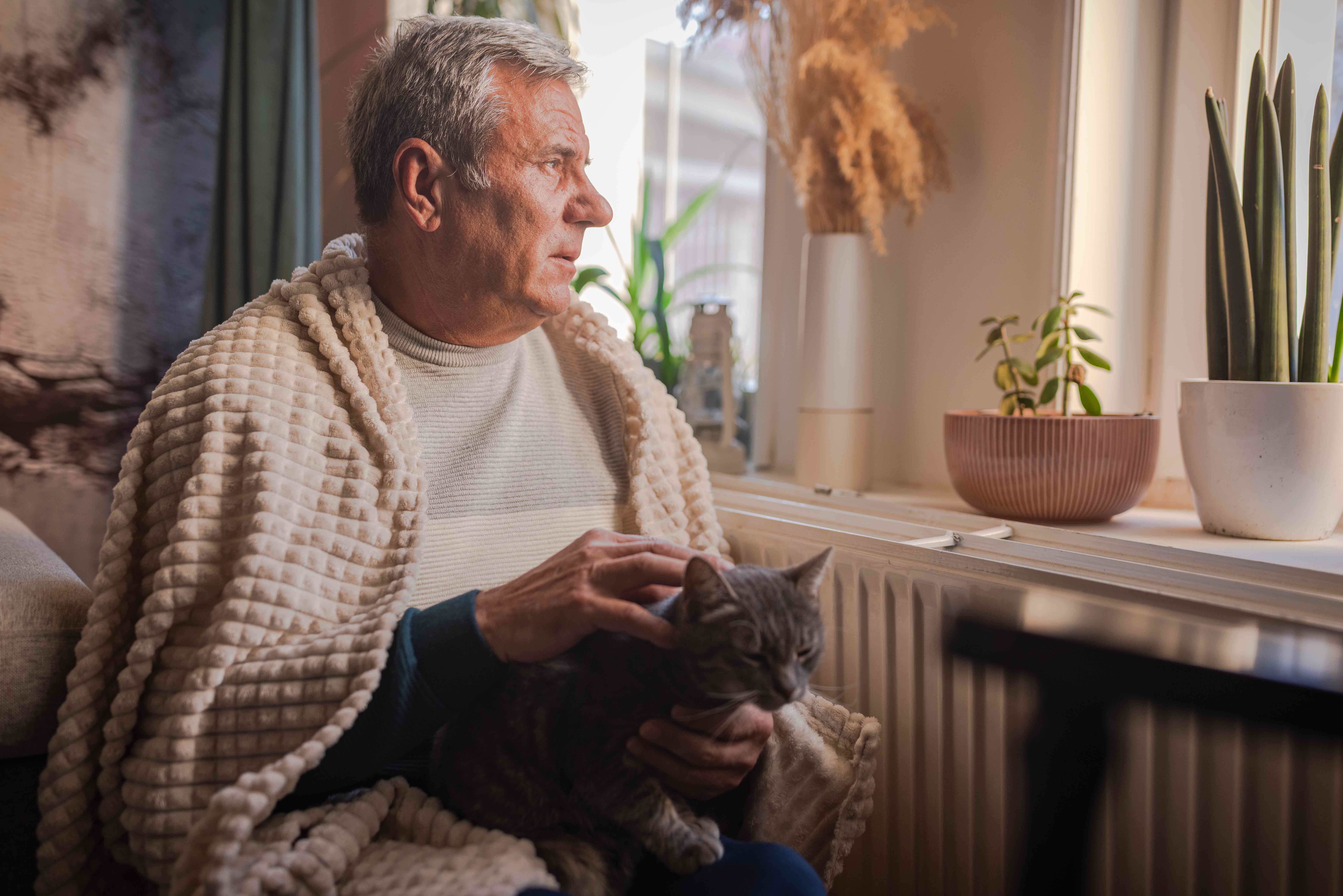 A man with his cat wrapped in a blanket