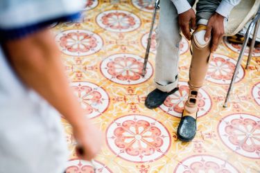 A man fitting a leg prosthetic while a medical professional looks on