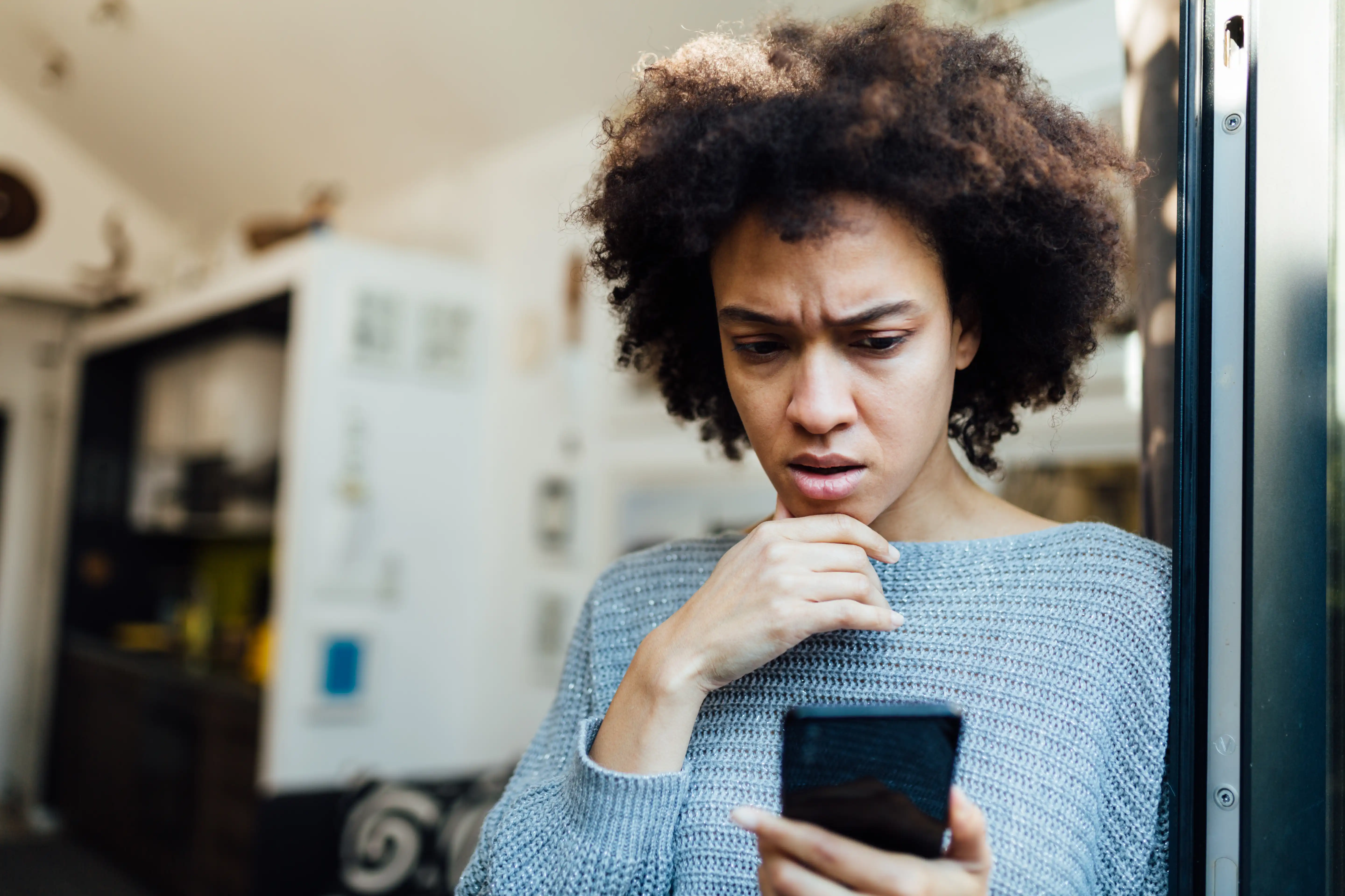 A woman frowning at comments on her phone