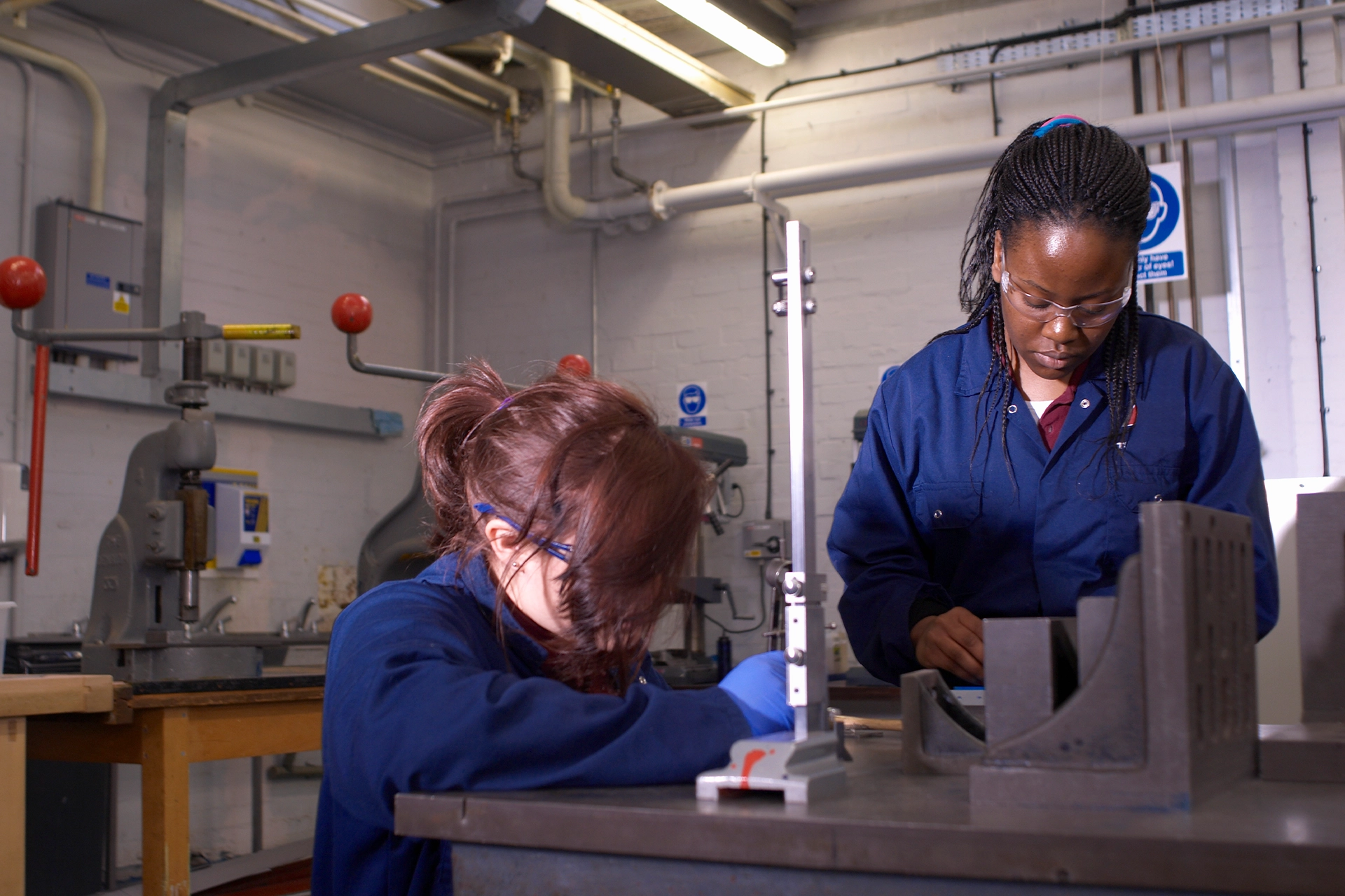 Two women in overalls working in a workshop 