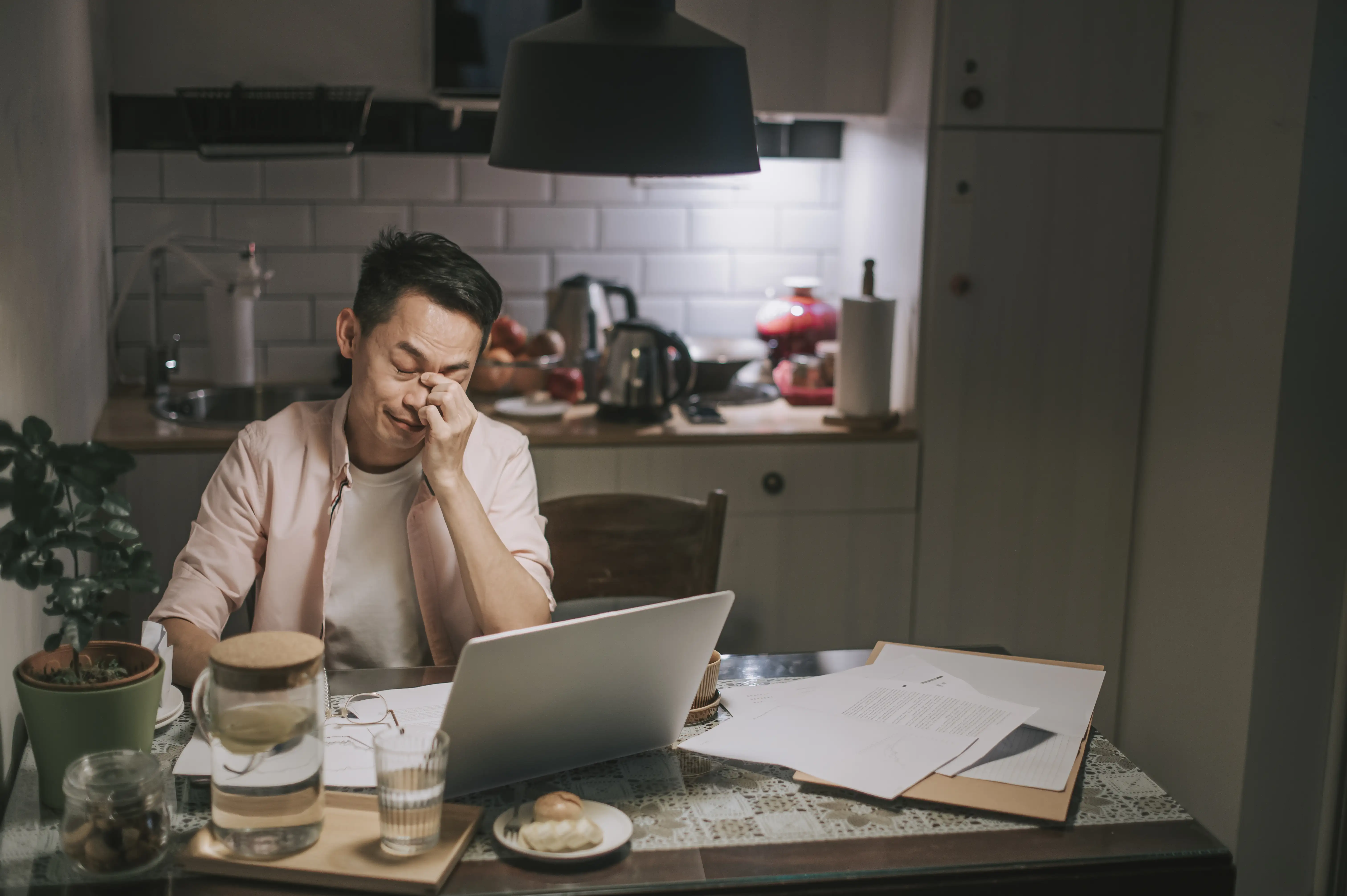 A man working late at home in emotional stress with his financial bills