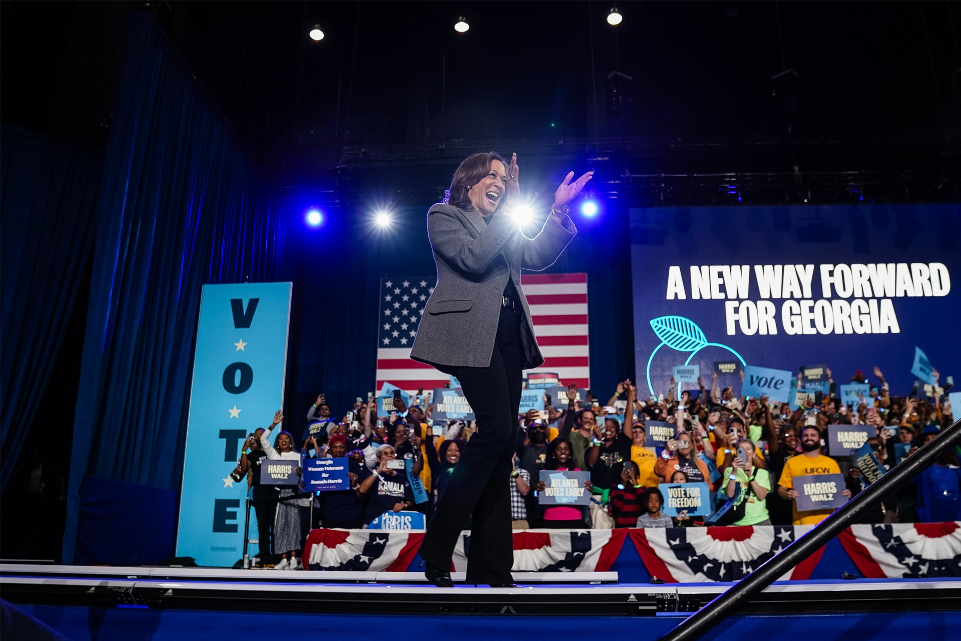 Kamala Harris on stage at Democratic event in Georgia, clapping and smiling to audience