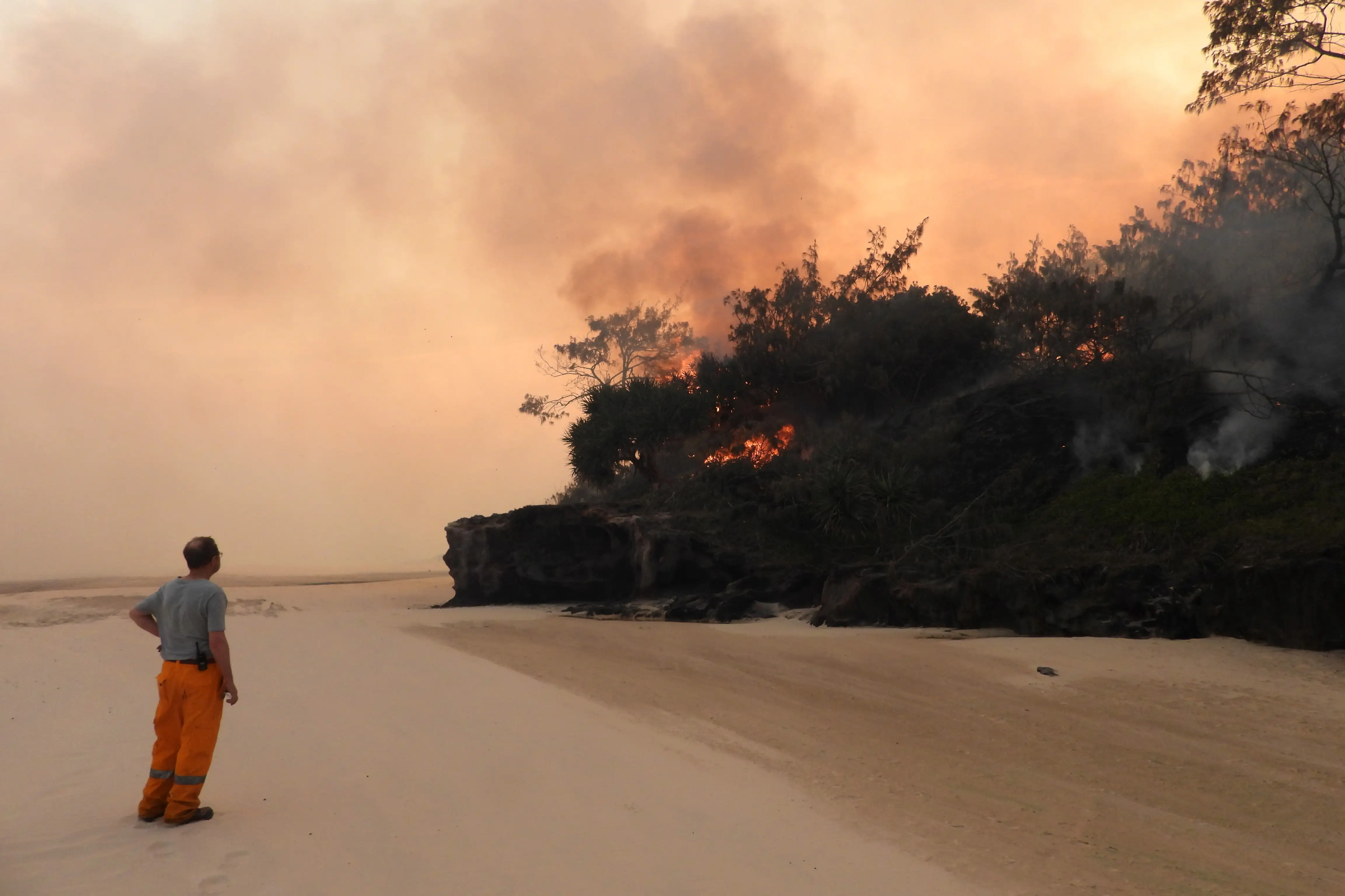 A volunteer fire-fighter watches a slow burning fire move along the beach