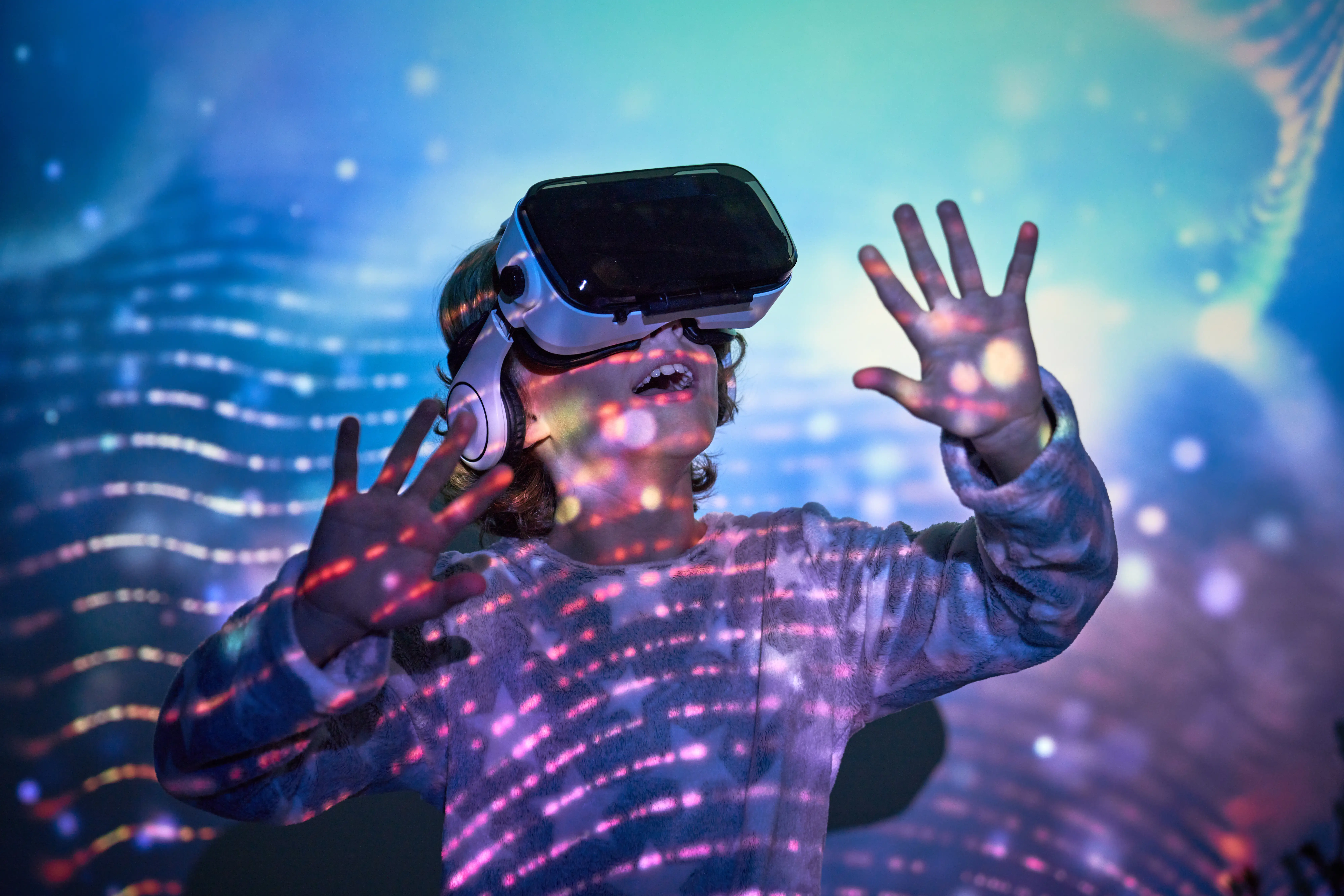A child uses a VR headset with projections of planets around him