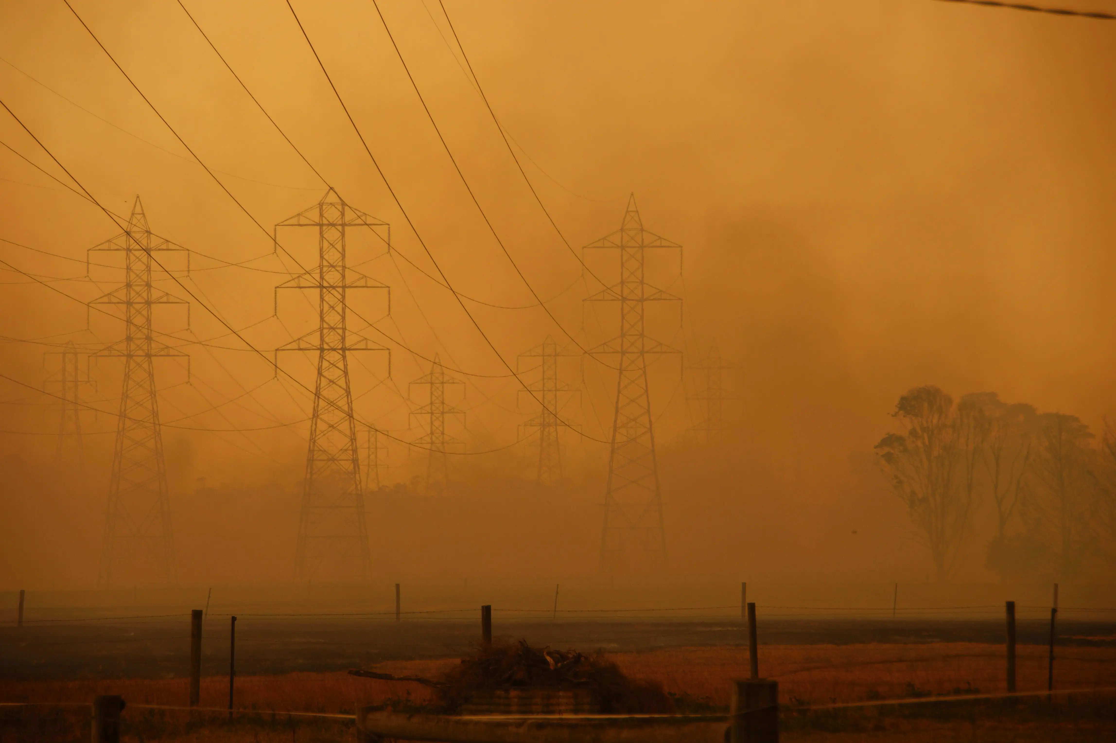 Power lines and energy infrastructure against an orange sky  and smoke during the Black Saturday bushfires in 2009