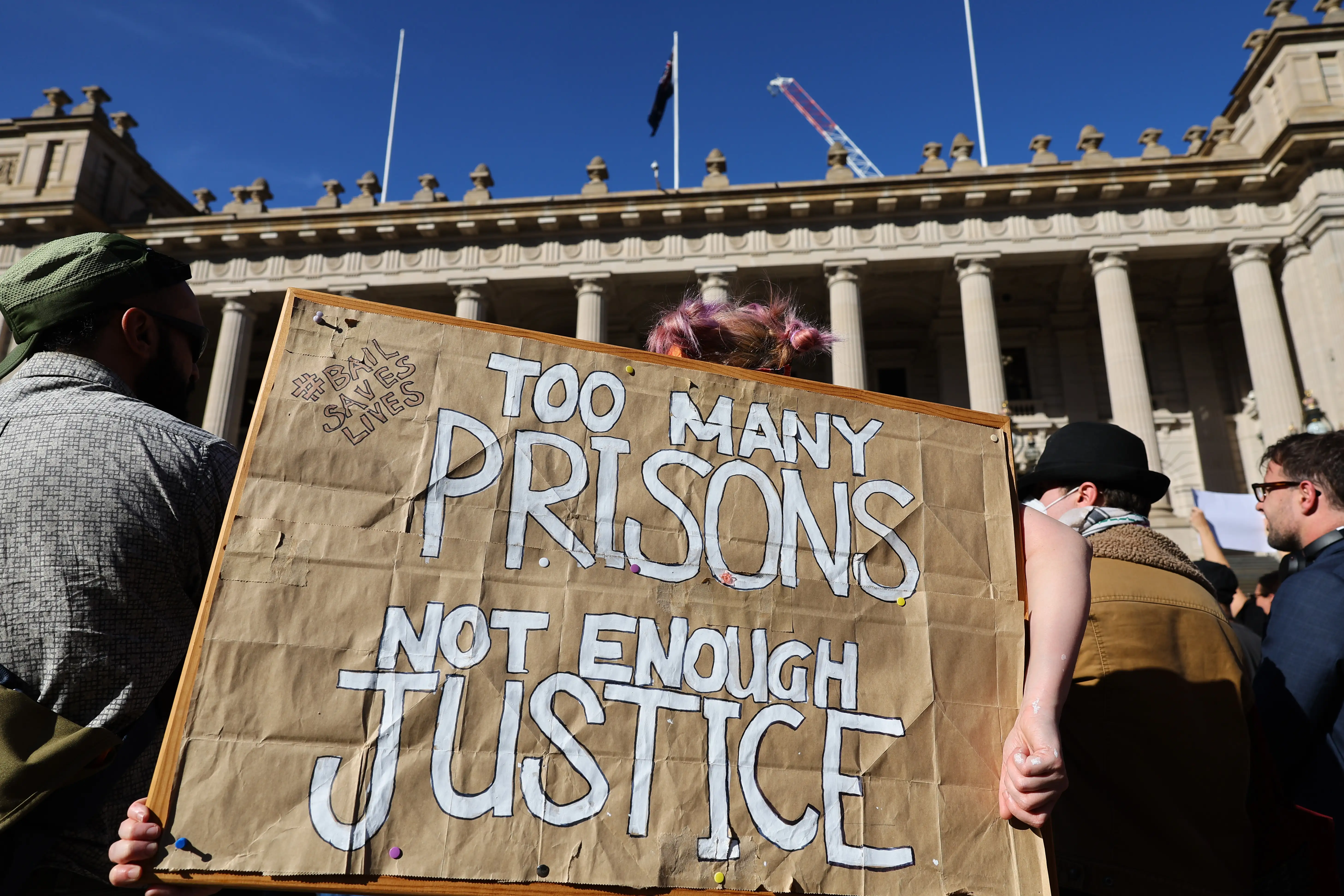 People gather with placards during a Bail Saves Lives protest outside Victorian Parliament, in Melbourne, 2025