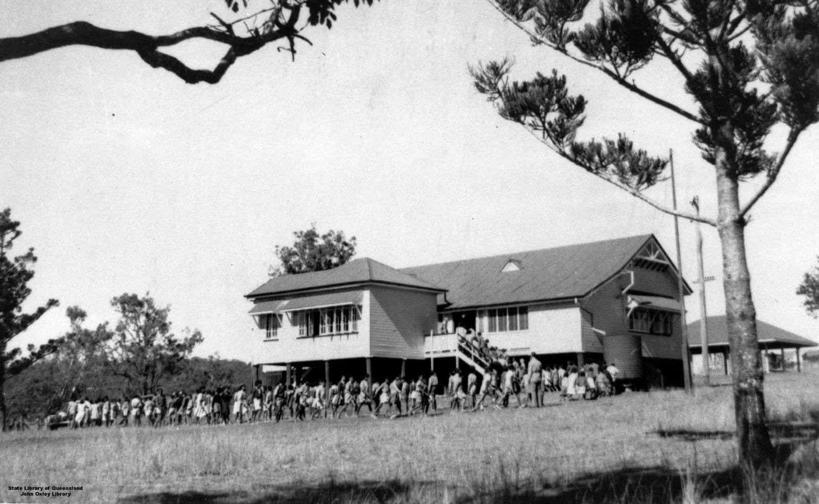 Aboriginal schoolchildren entering the school building at Cherbourg State School, ca. 1956