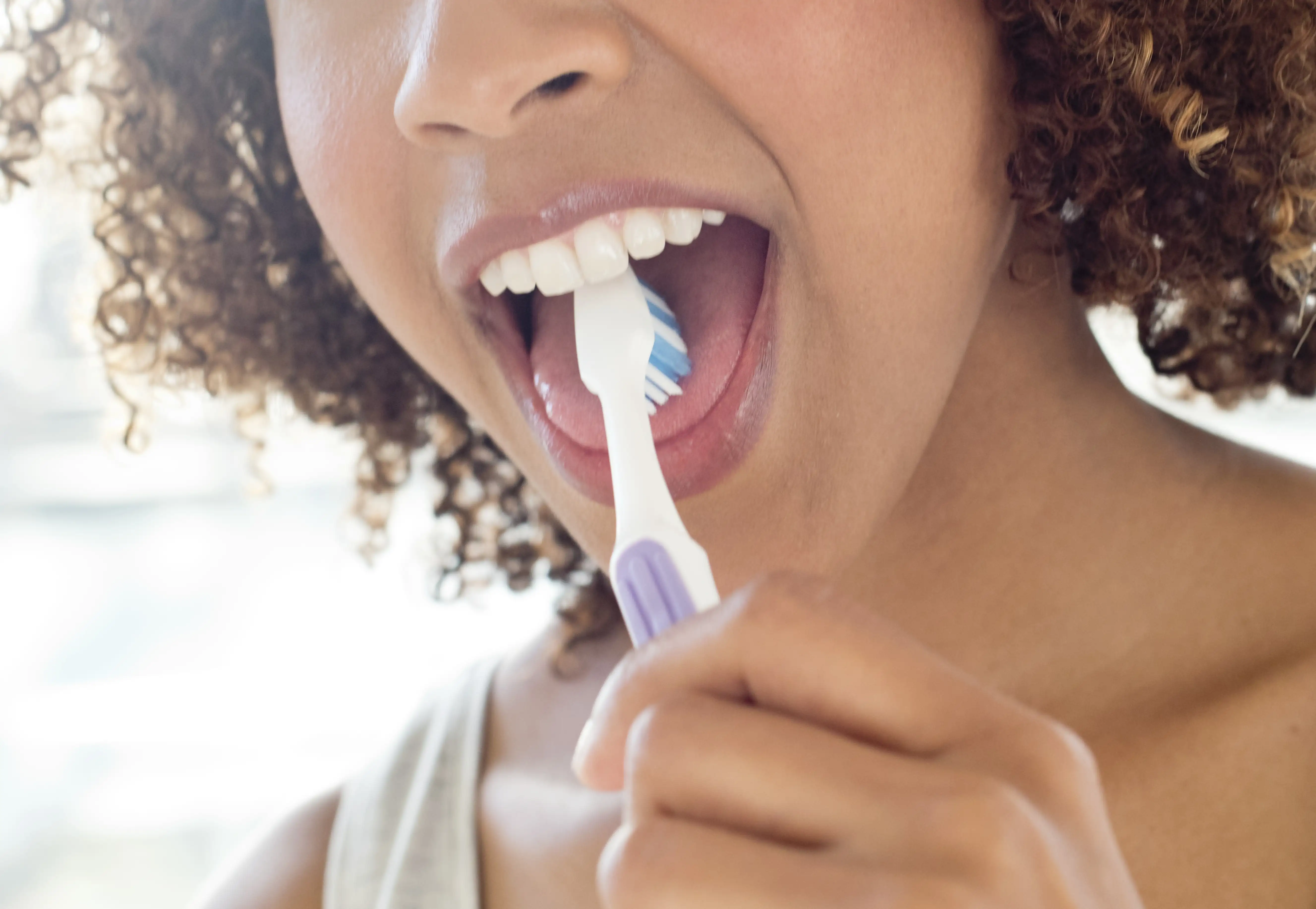 A woman using a toothbrush to clean her tongue