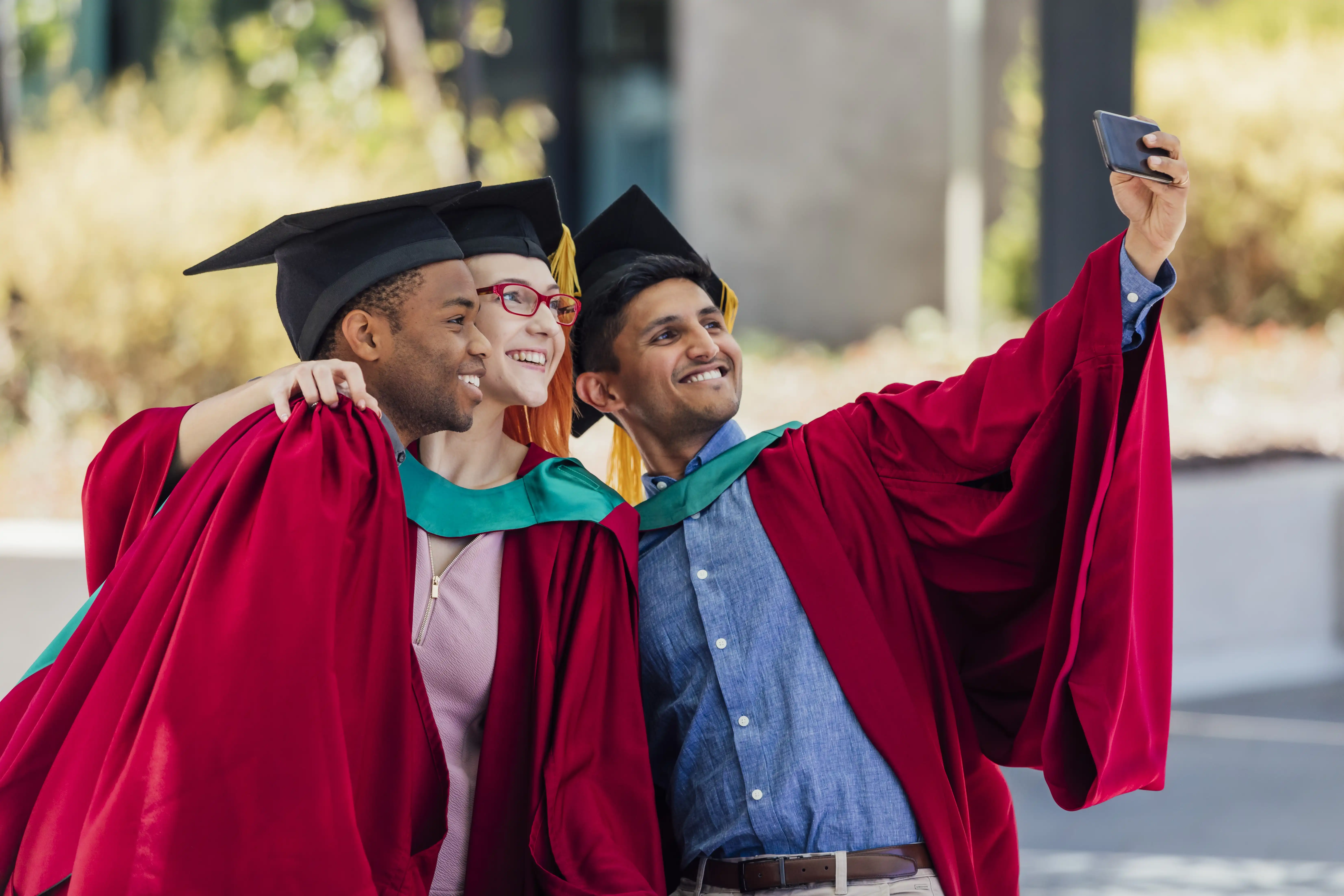Three university students take a selfie in their graduation outfits
