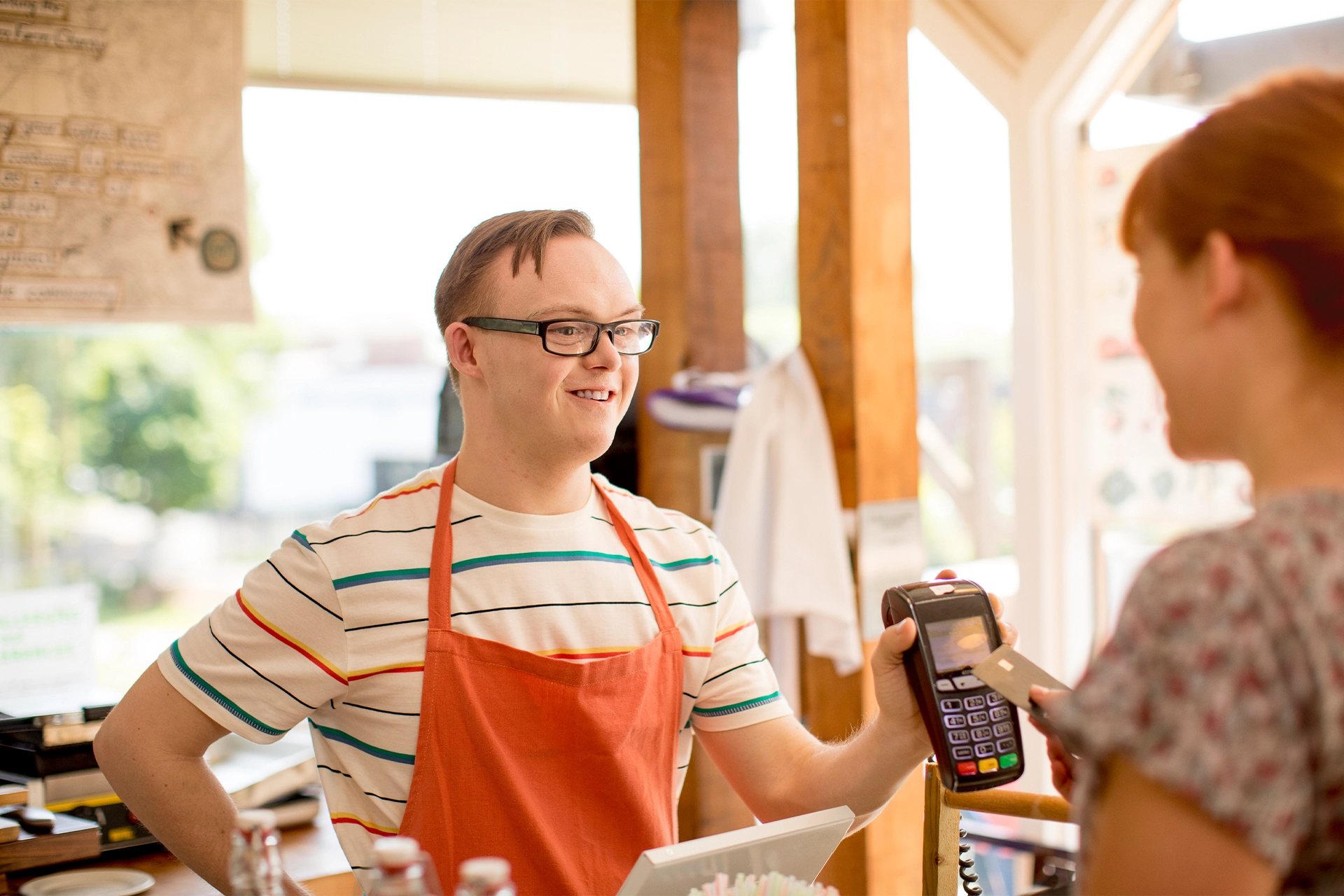 Man with Down's Syndrome serving a happy customer in a cafe