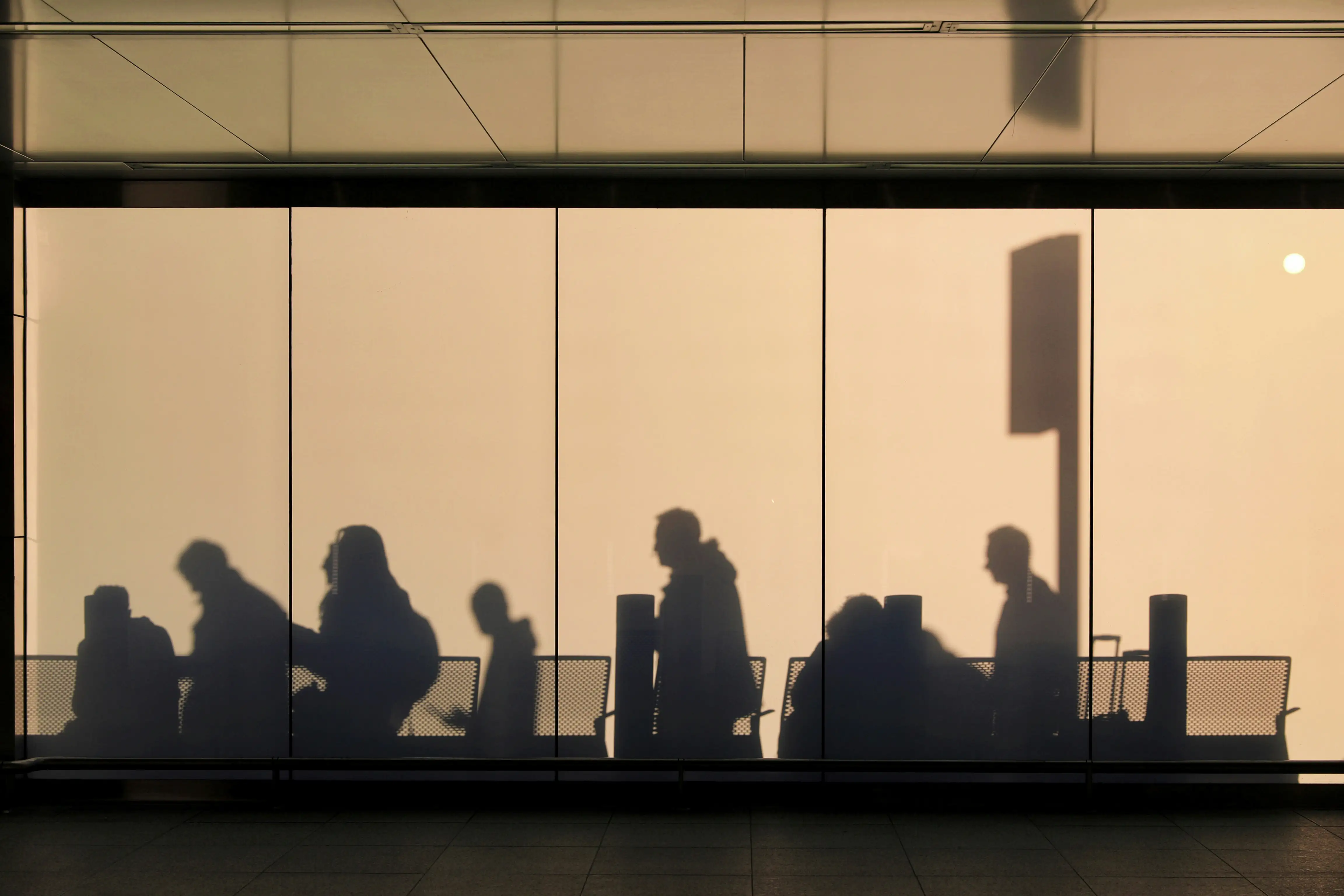 Shadows of people queuing against a wall