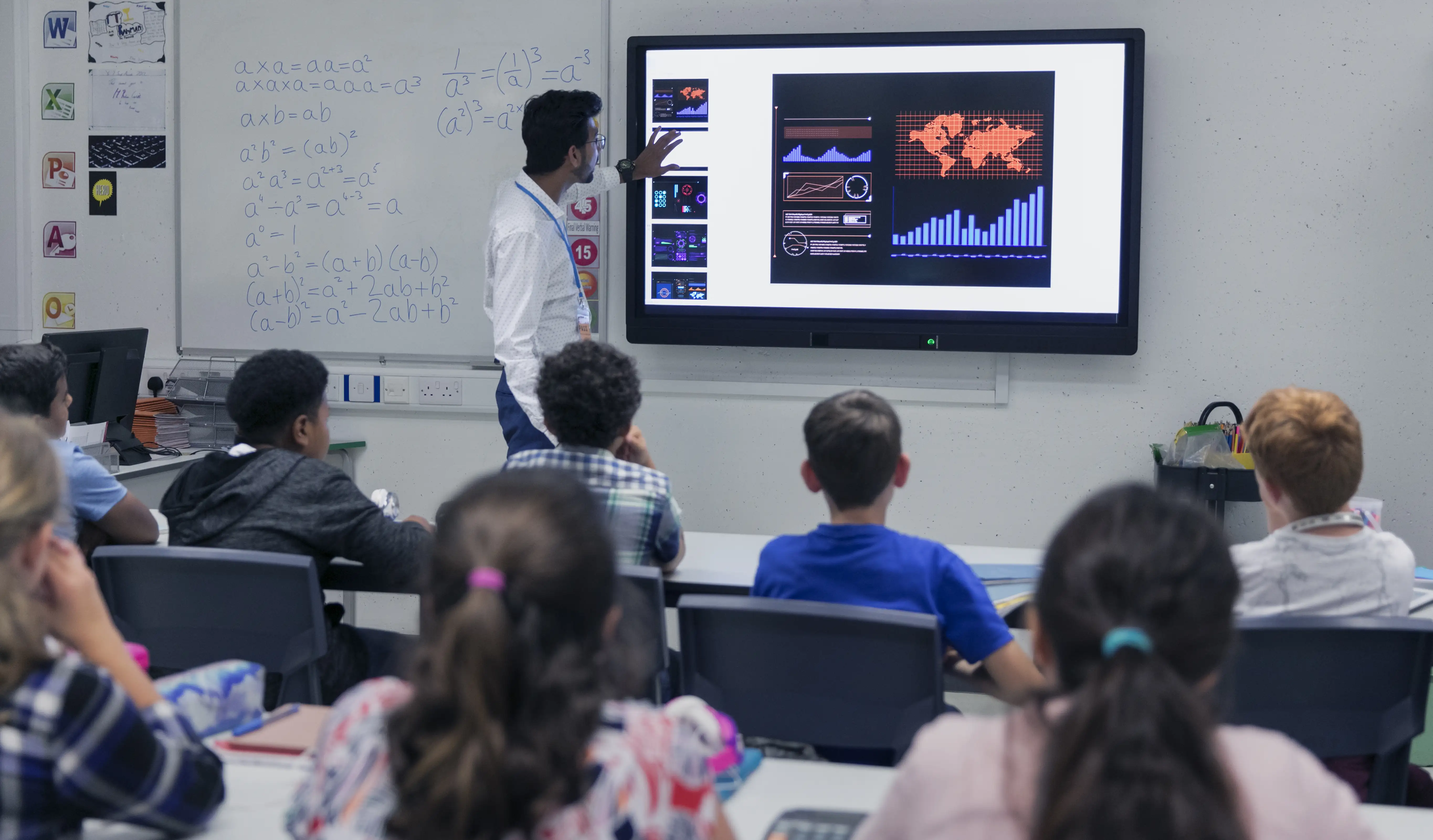 Male teacher leading lesson at touch screen television in classroom