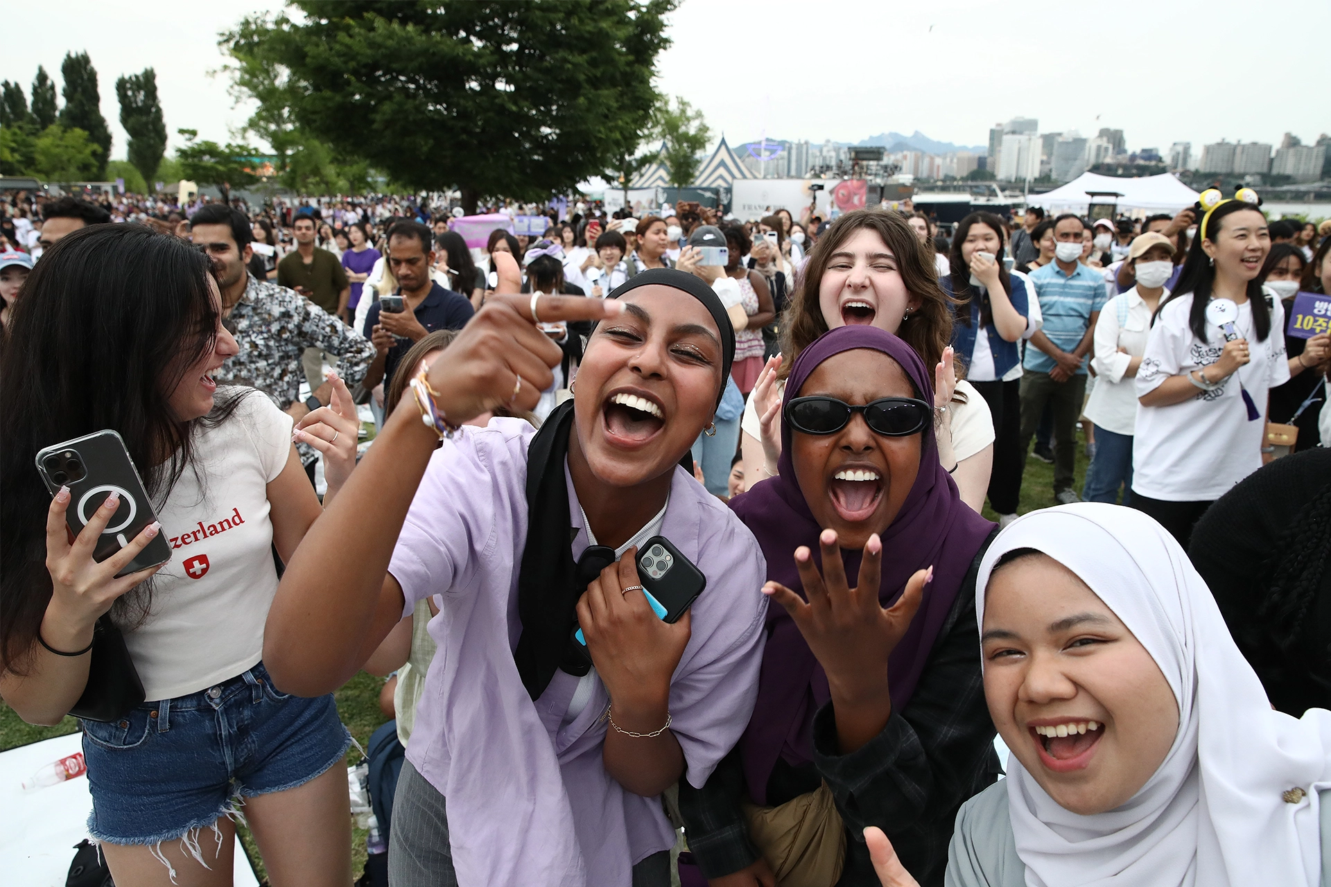 Group of girls smiling and cheering at a K-Pop concert