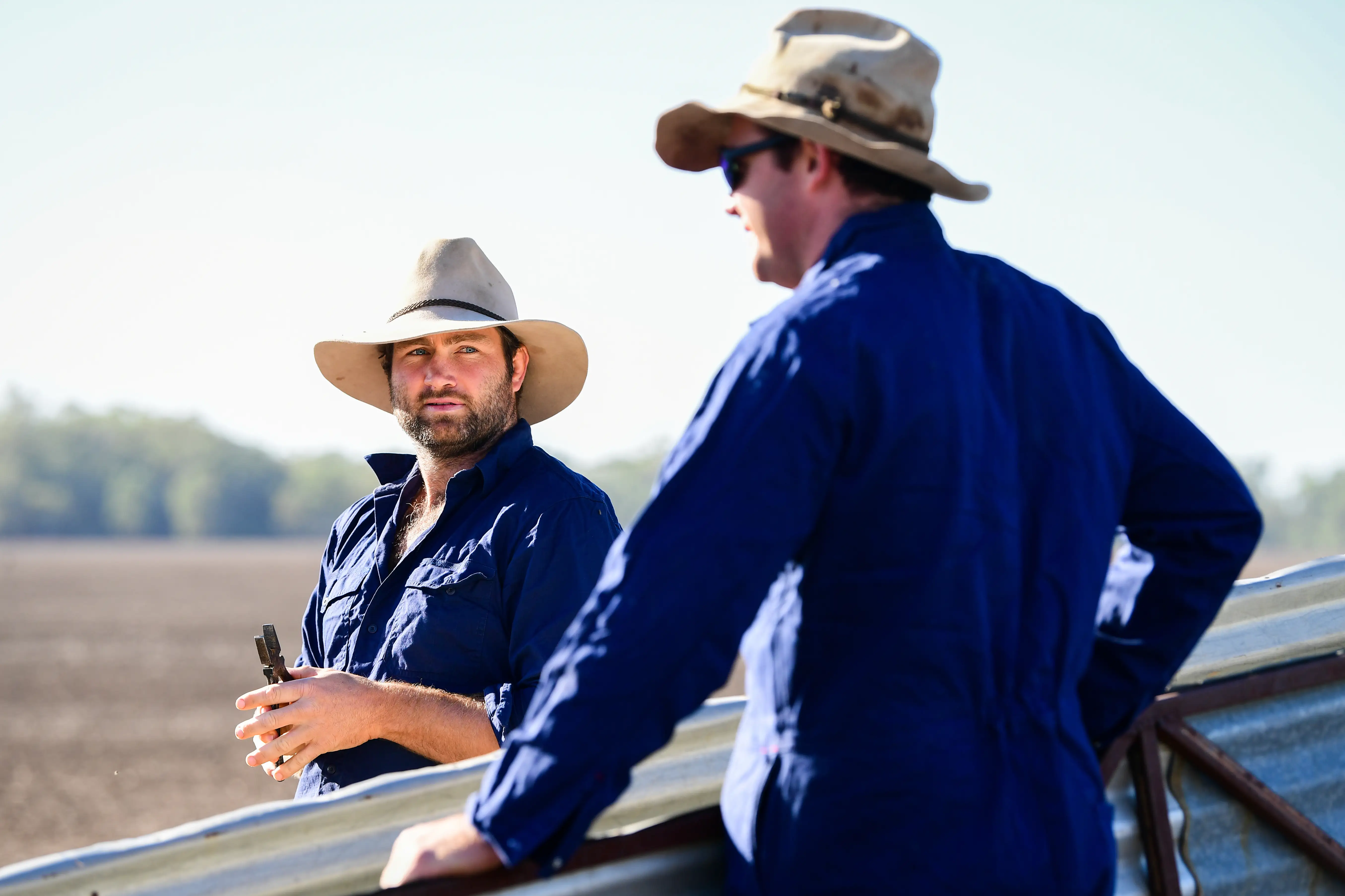 Two men wearing hats and long-sleeve shirts in the country