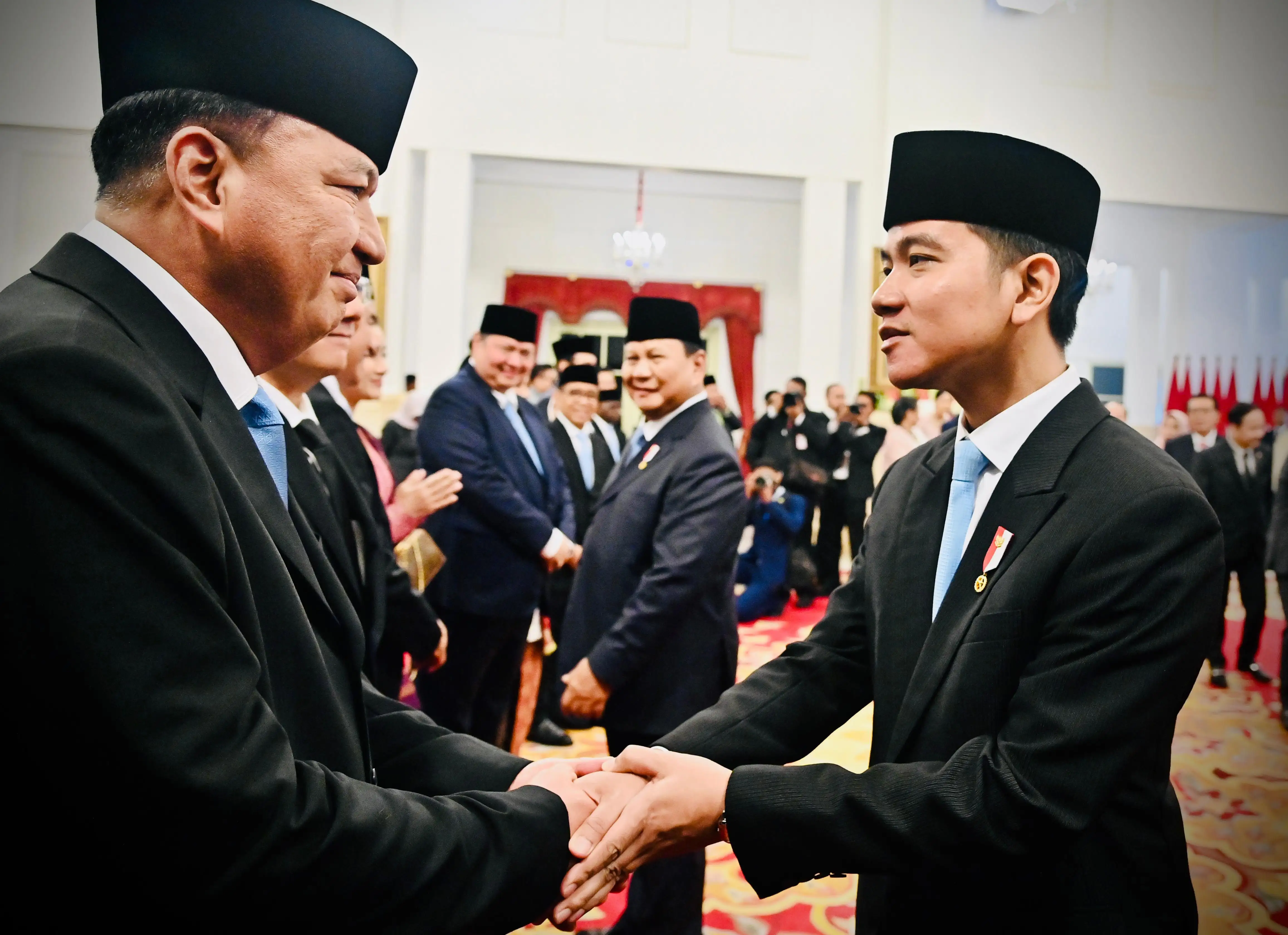 Indonesian Vice President Gibran Rakabuming Raka shaking hands with new ministers.