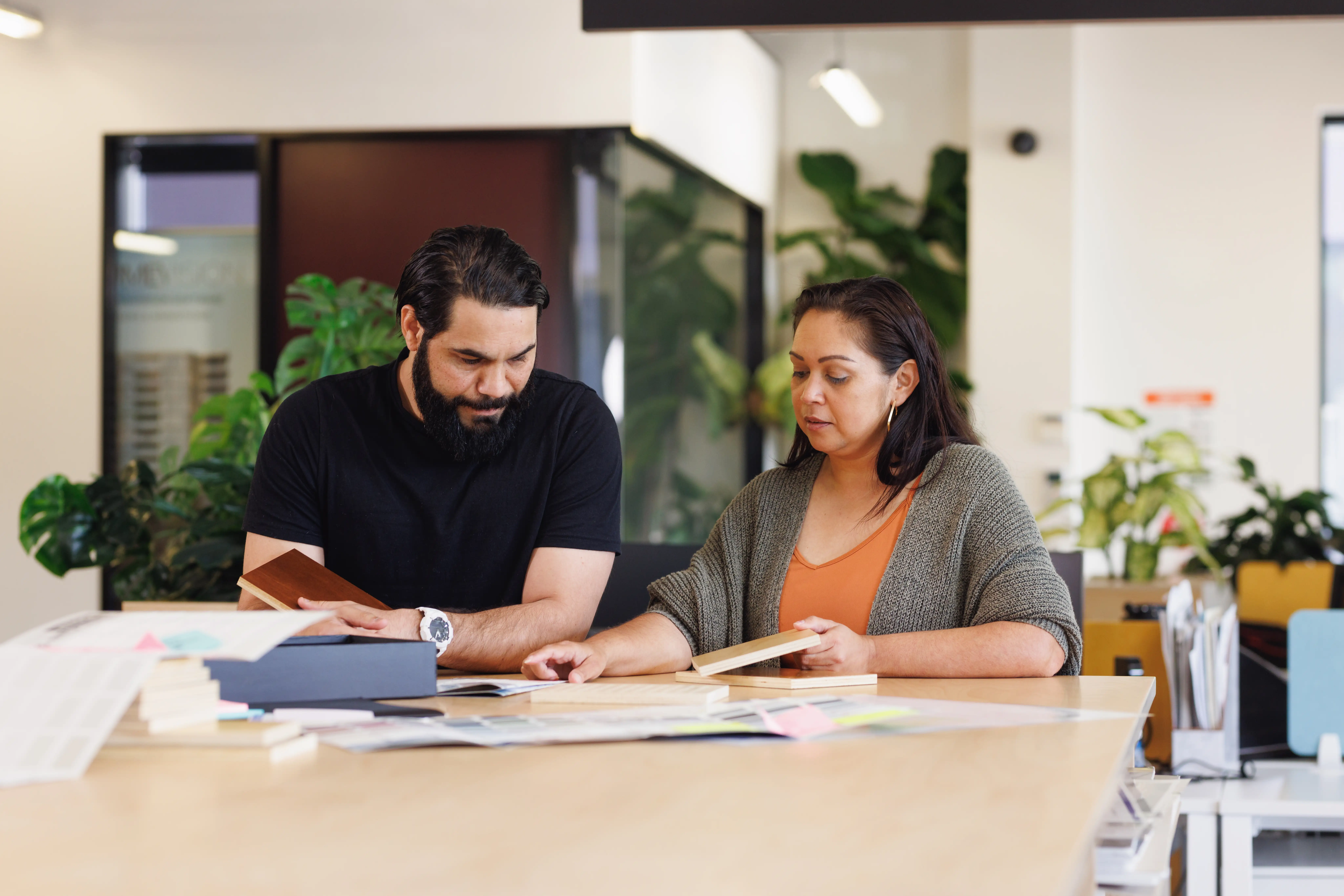 Male and female Aboriginal Australian designers collaborating in modern open workspace.