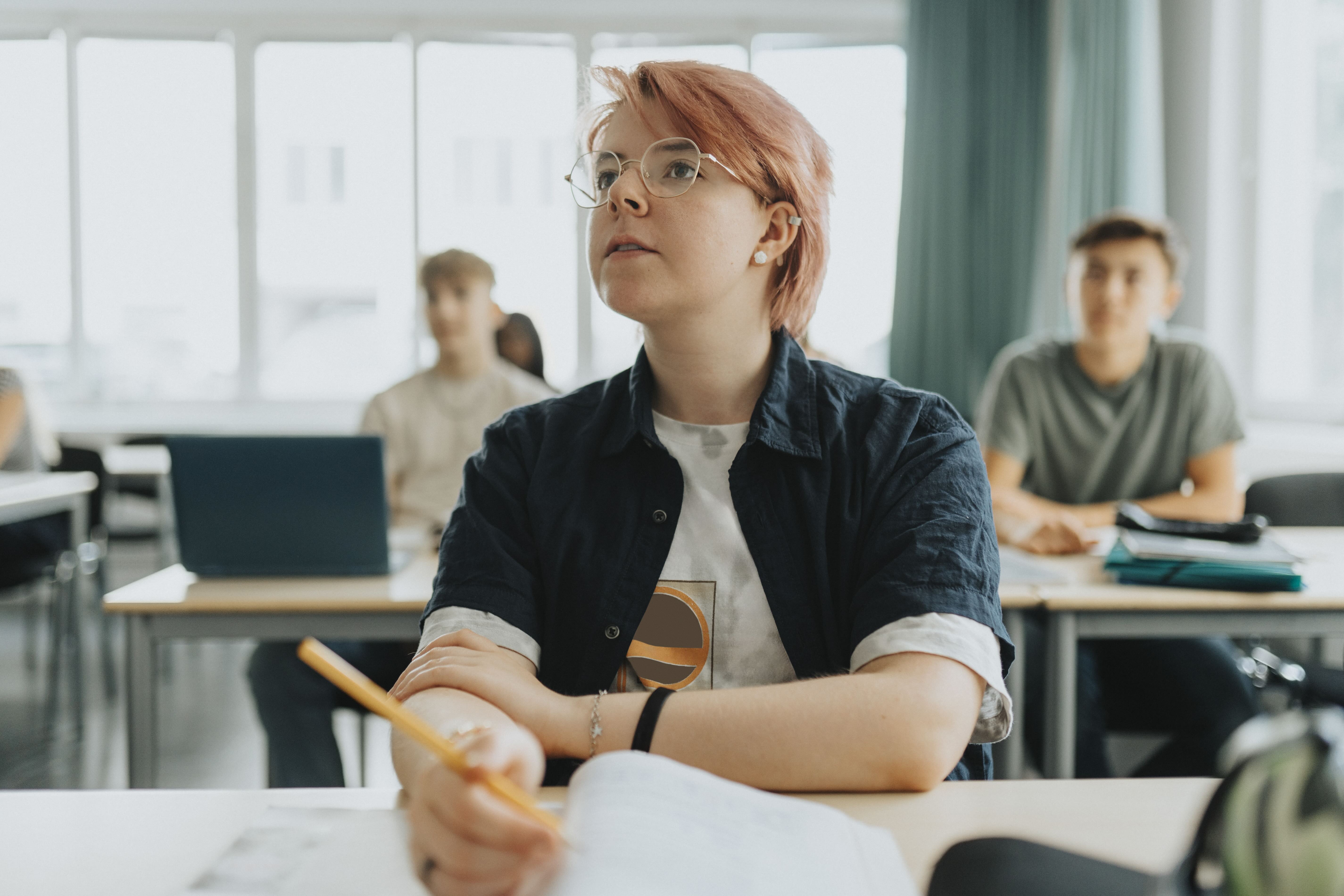 Non binary person sitting at school desk