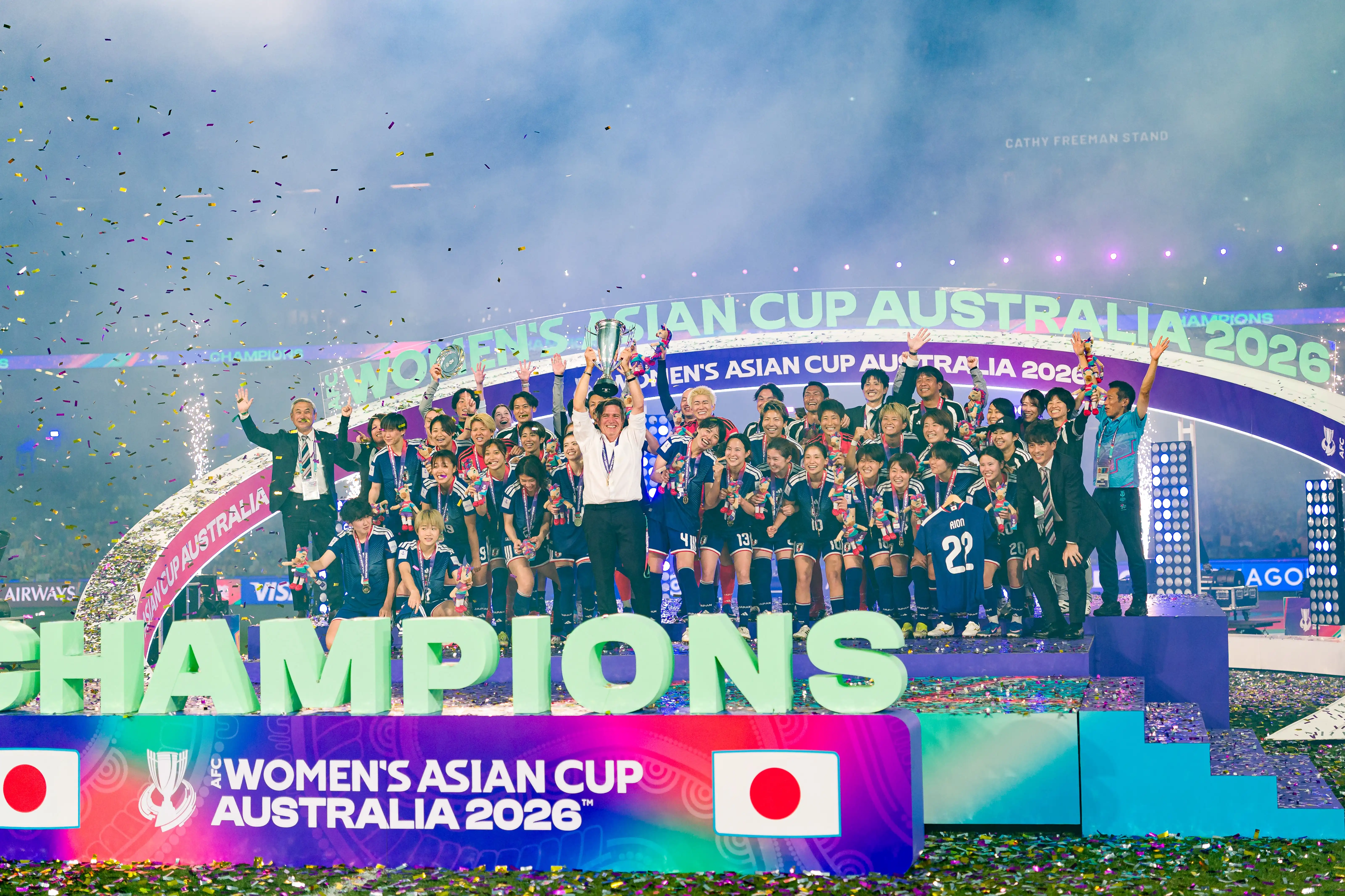Coach Nils Nielsen holds the Asian Cup trophy aloft on stage with the whole Japanese women’s soccer team who are cheering as confetti falls from the skyir success at the Asian Cup, both Nielsen and Blayney lost their jobs. Picture: Getty Images