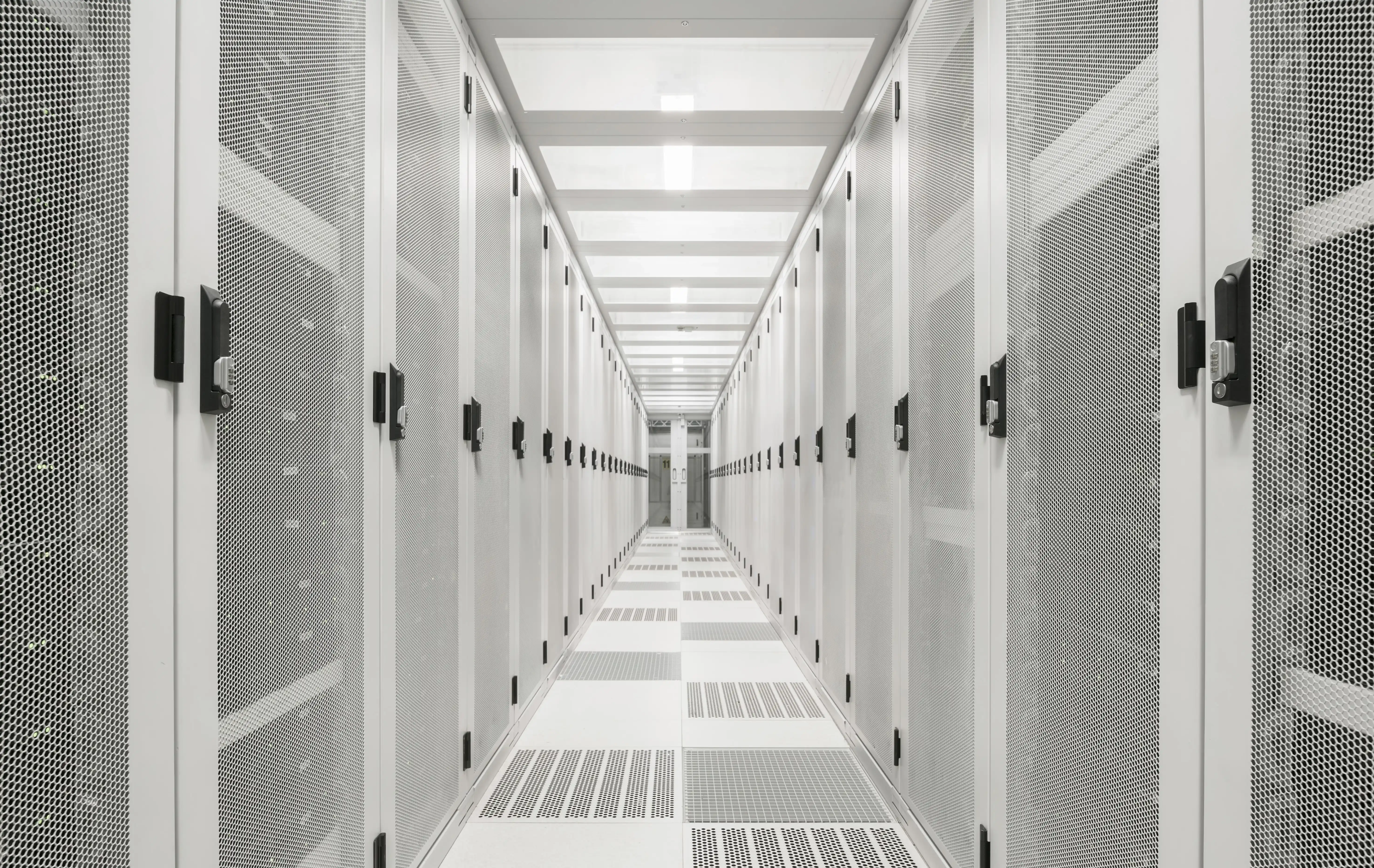 A starkly white hallway with tall cabinets on either side in the server room at a data centre