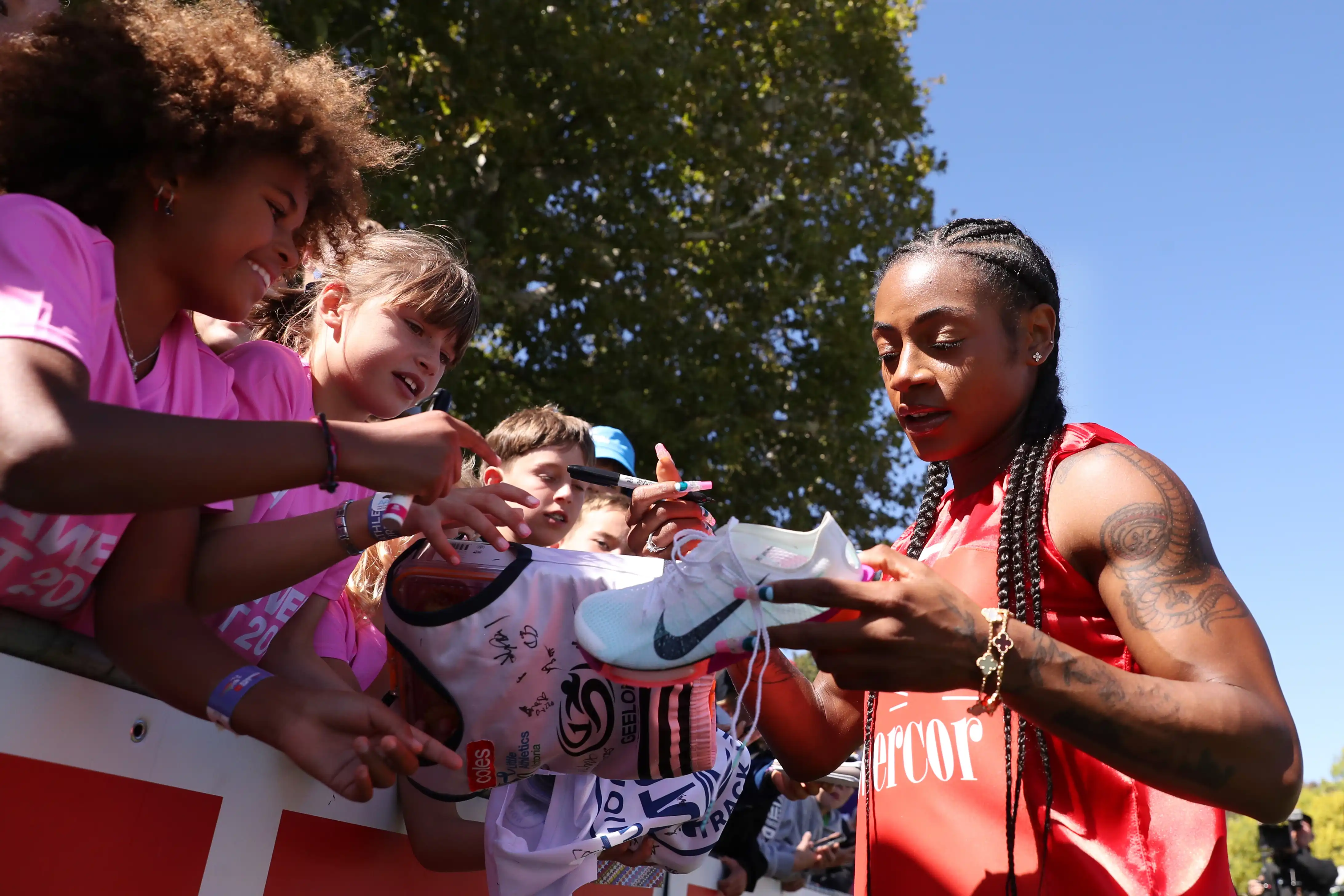 A female athlete signs shoes and clothes of fans after a race