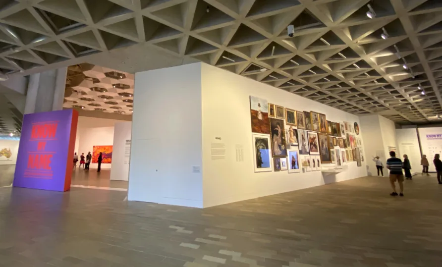 A modern gallery space with paintings on the wall and people standing around