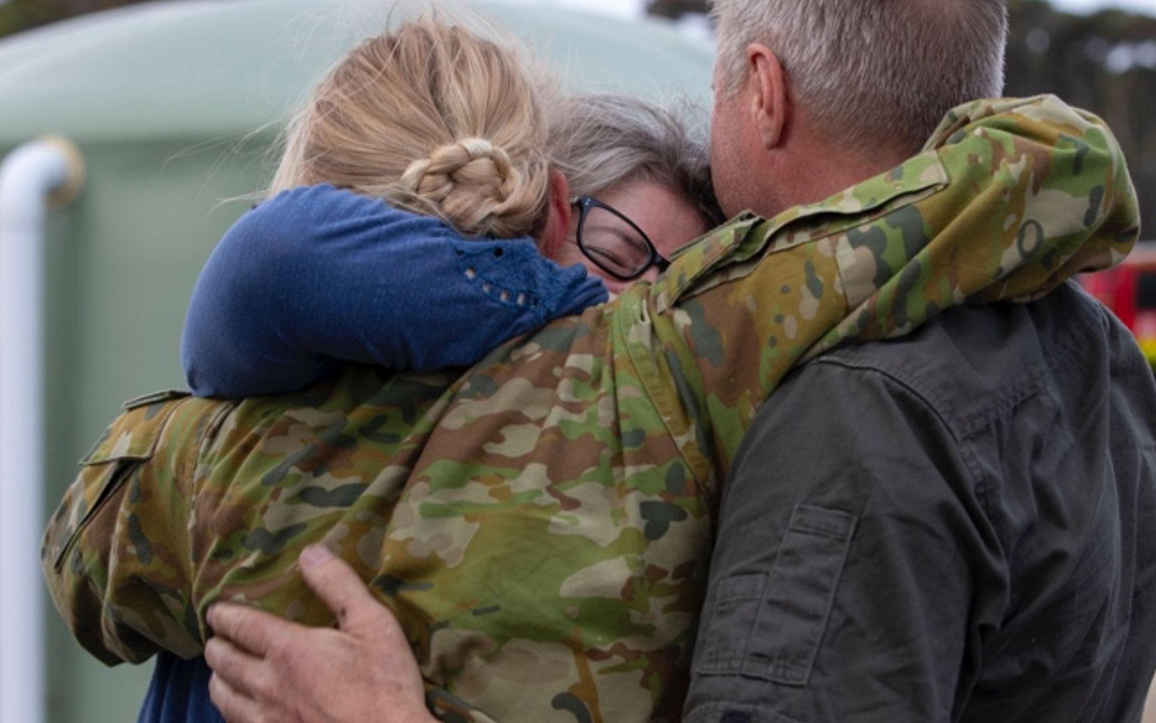 A women in army uniform hugs her family