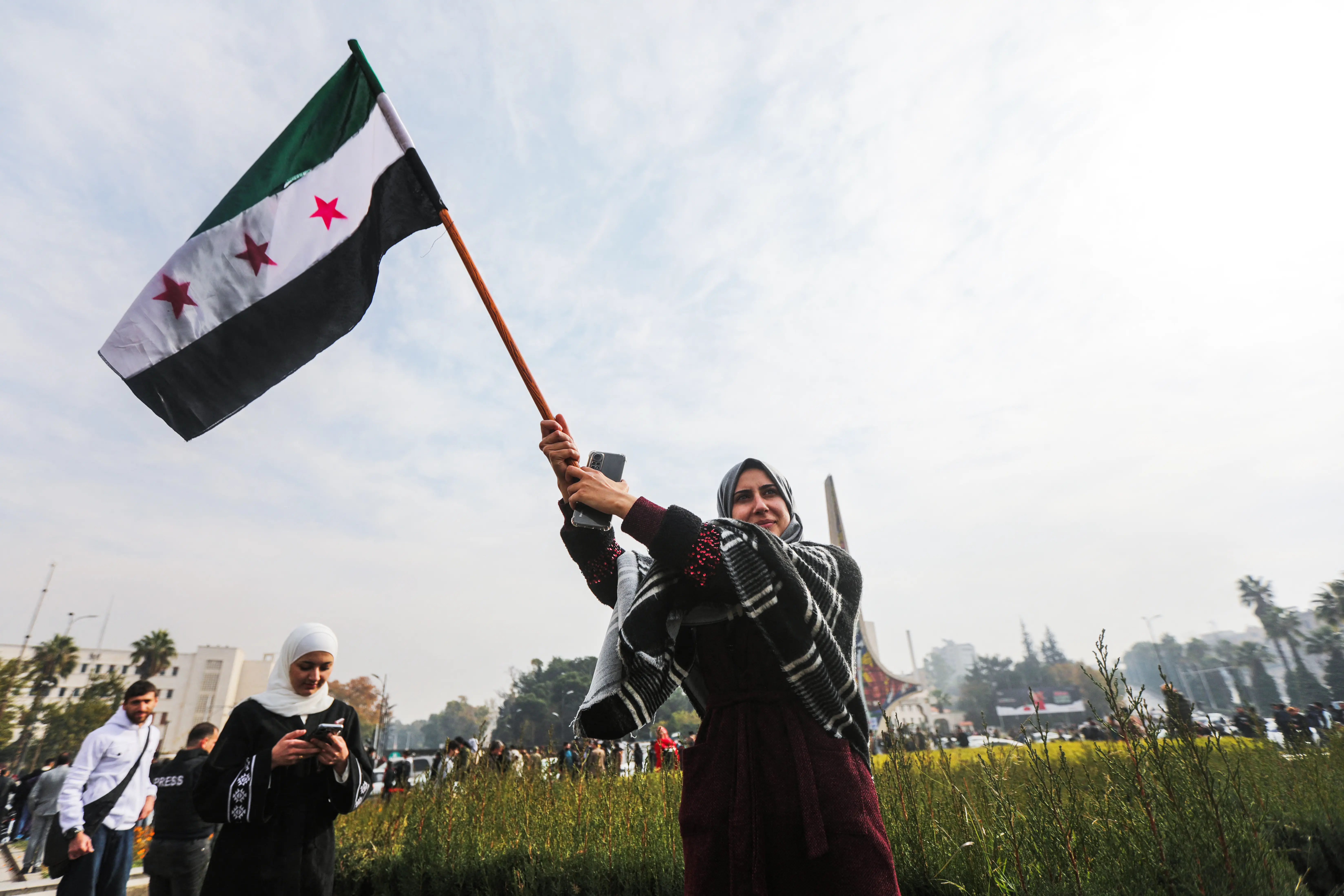  A woman waves a Syrian opposition flag as she celebrates at Umayyad Square in Damascus