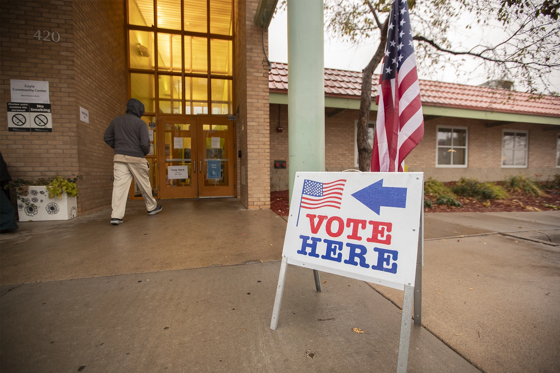 Man walking into US polling station, with sign out front saying: Vote Here