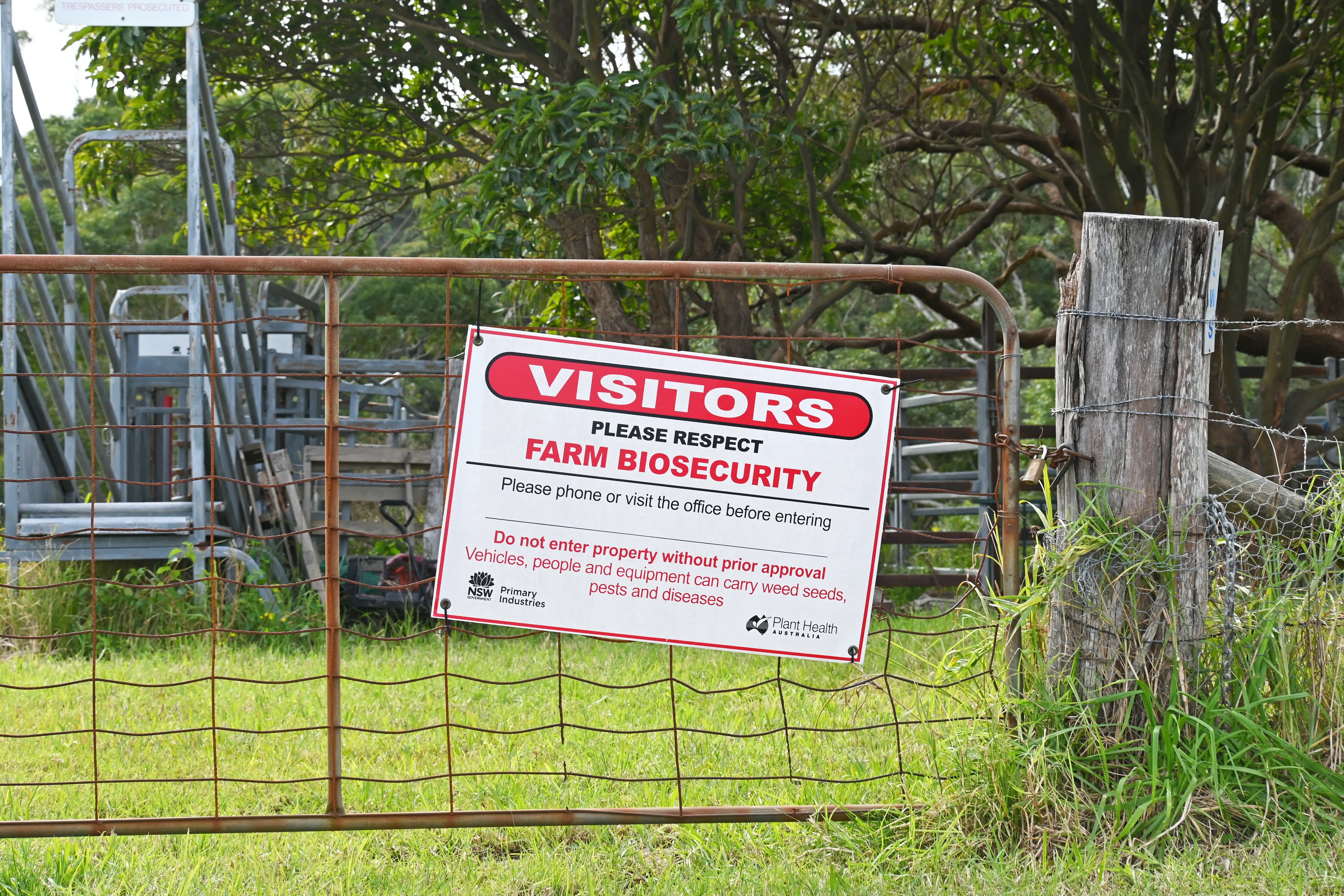 A biosecurity warning sign on a farm gate.