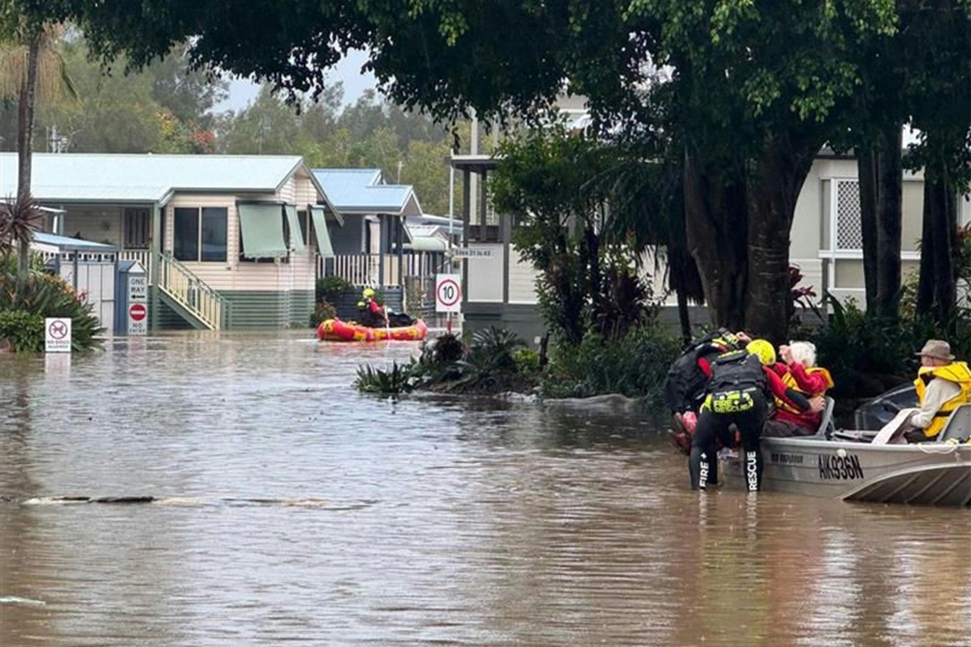 Elderly people being rescued on a boat in a flooded town street