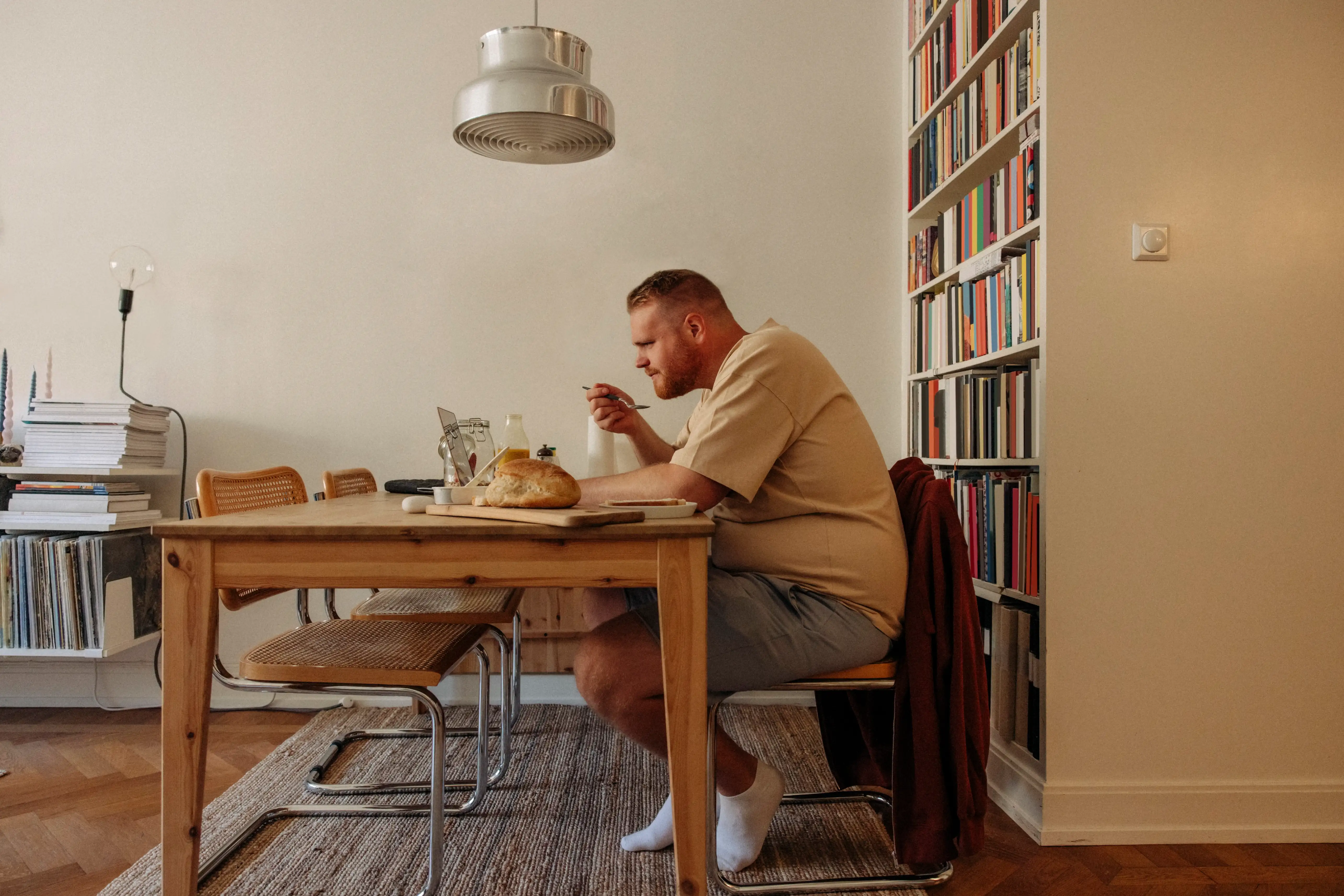 An overweight man sitting at a table with large portions of food in front of him