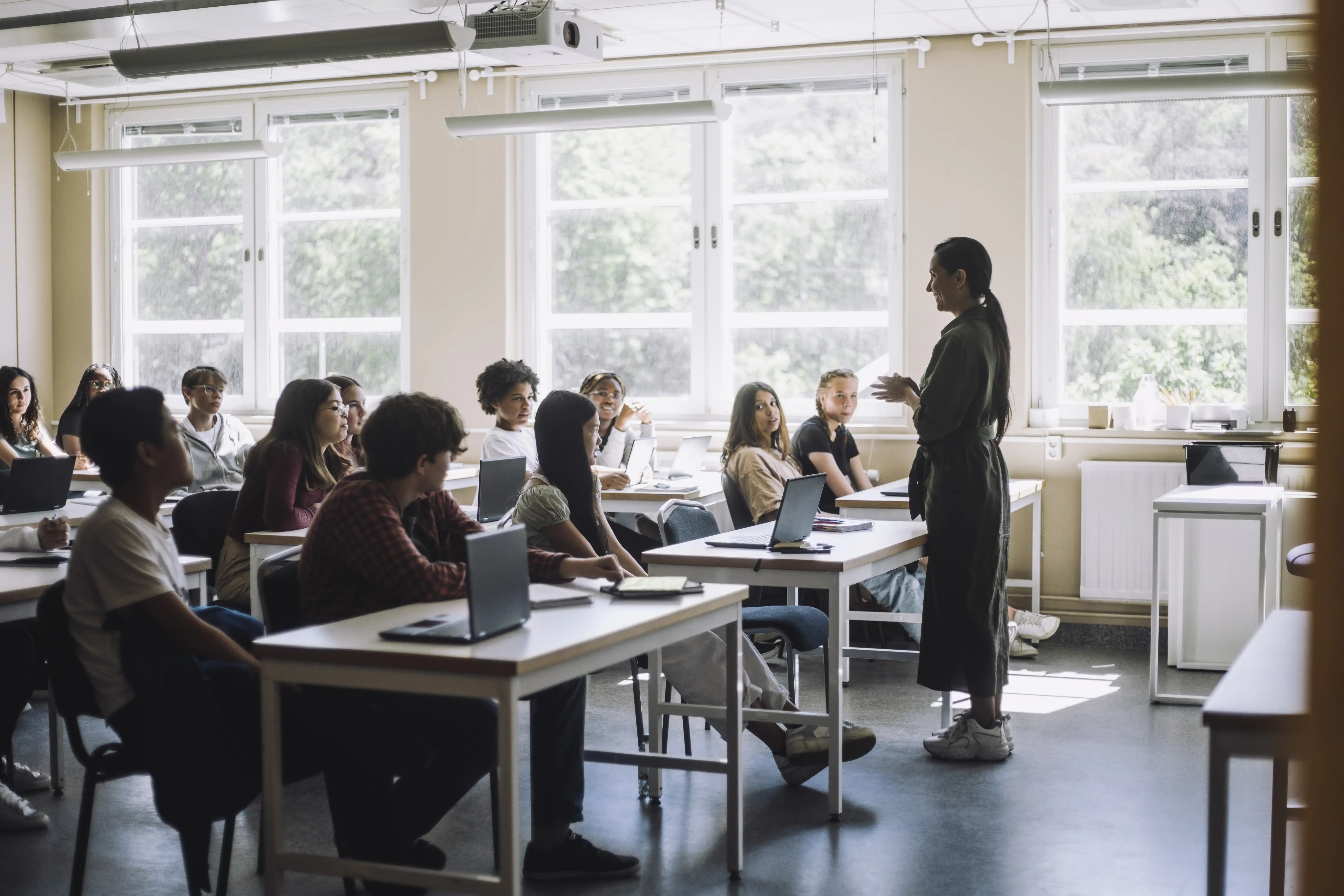 A woman stands at the front of a classroom teaching a room full of students