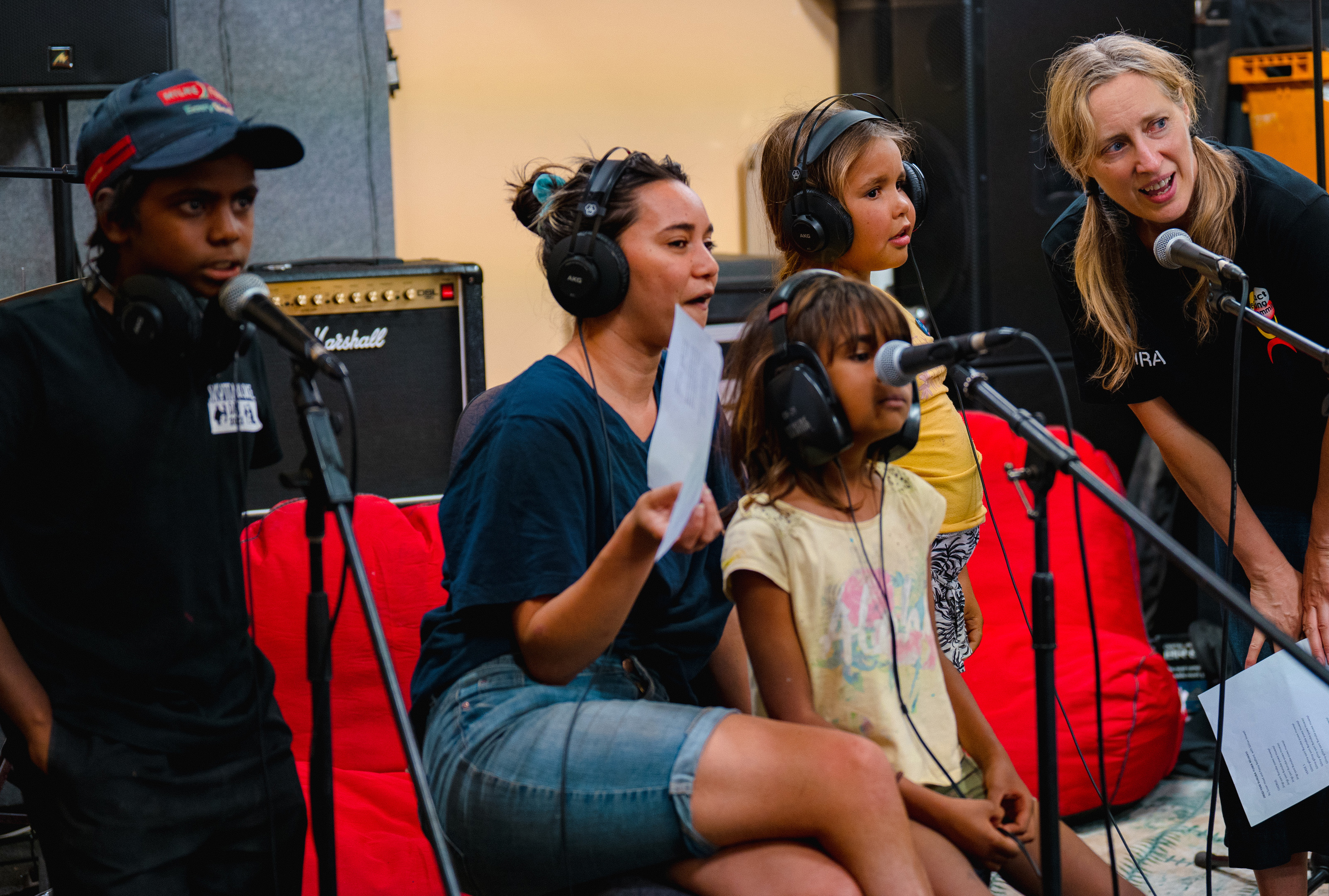 A group of children and women singing into microphones