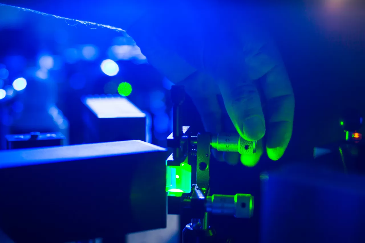 Hand adjusting lab equipment under blue and green lights