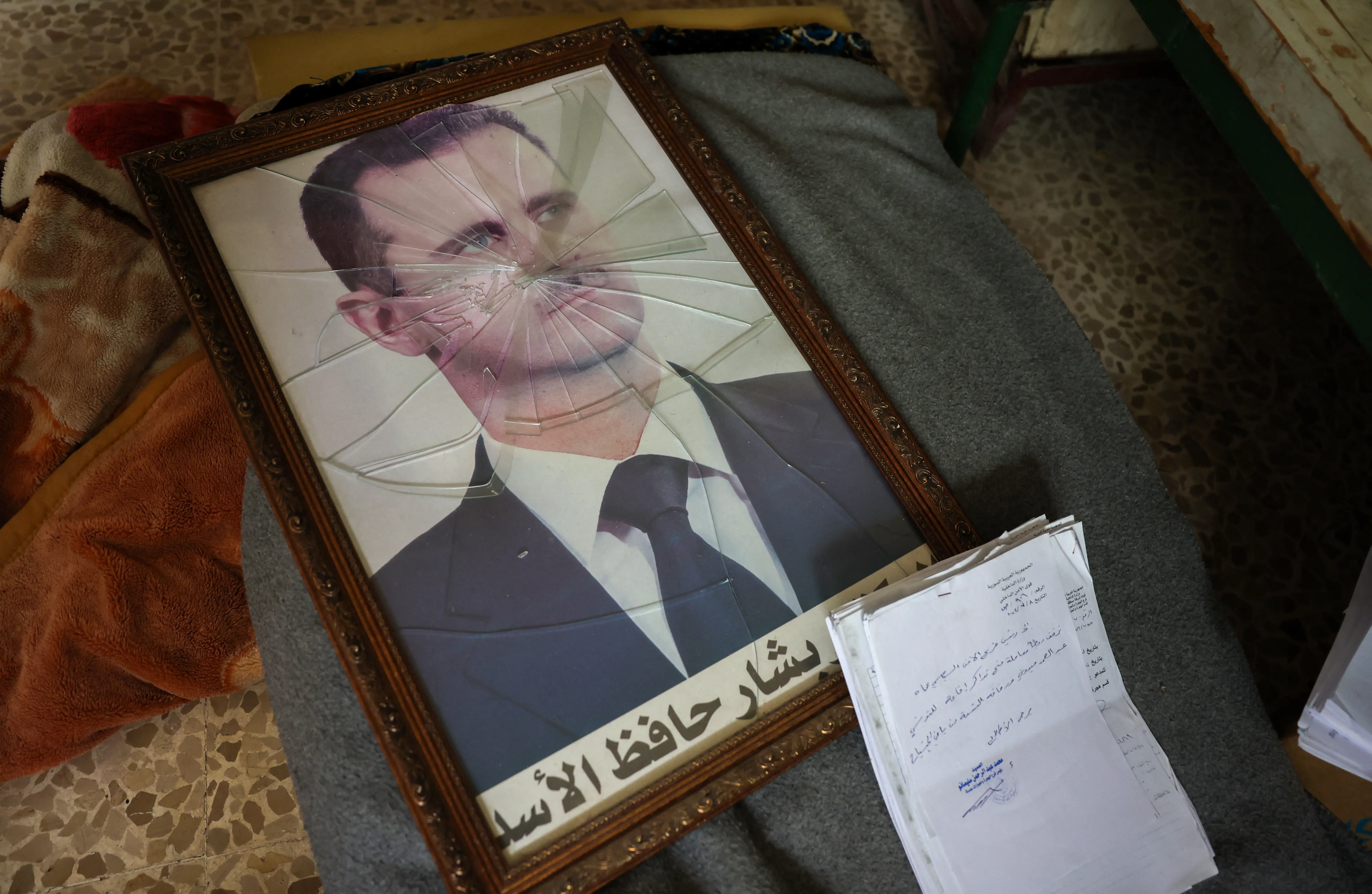 A portrait of Syrian President Bashar al-Assad is pictured with its frame broken