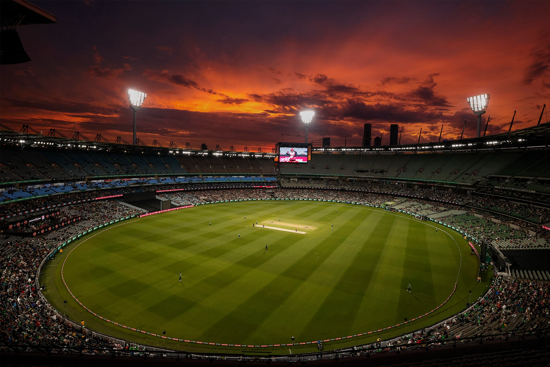 Overhead shot of Melbourne Cricket Ground at sunset, with crowd of people in stands