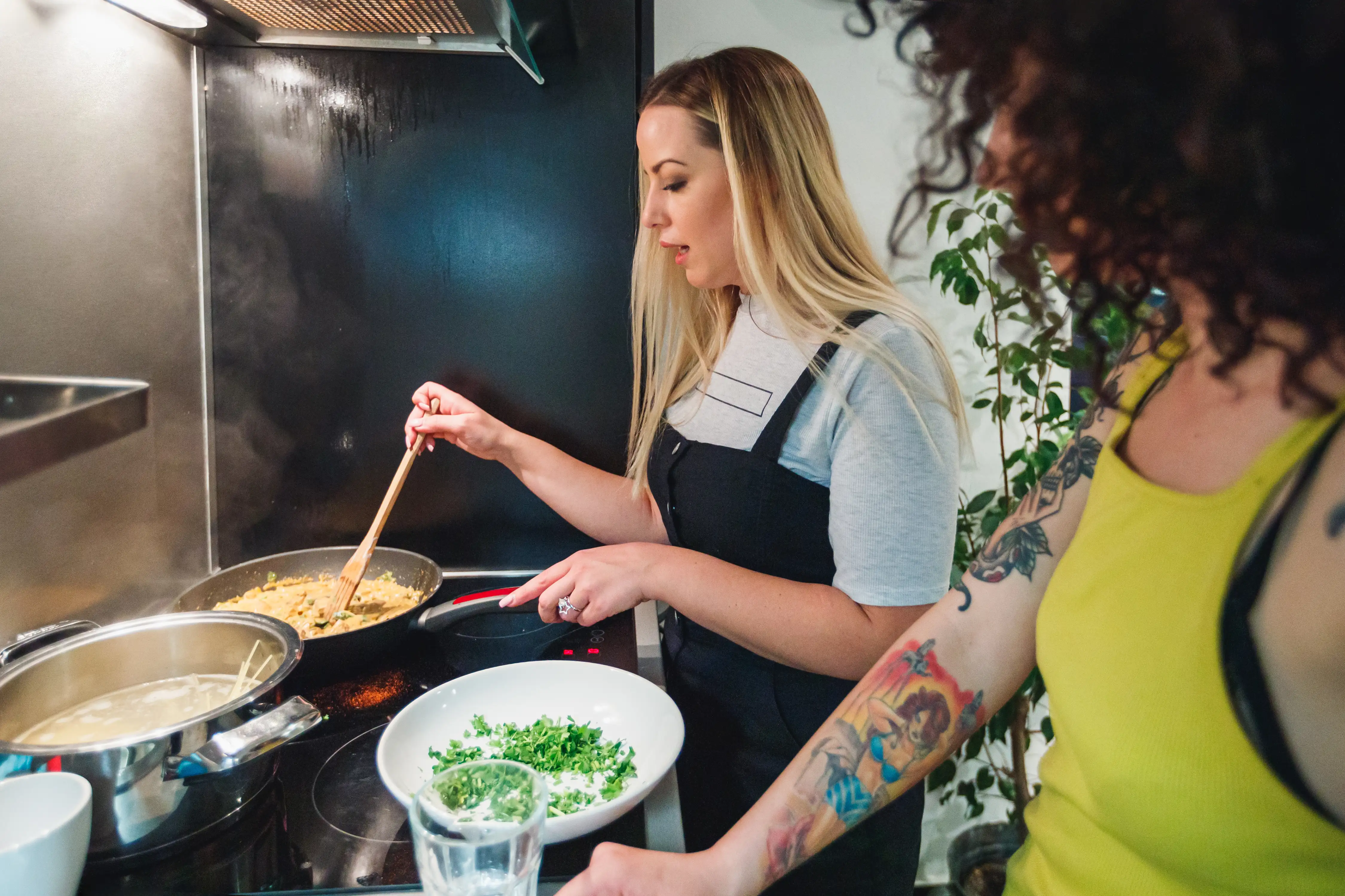 Two young women cooking together at the stove in the kitchen
