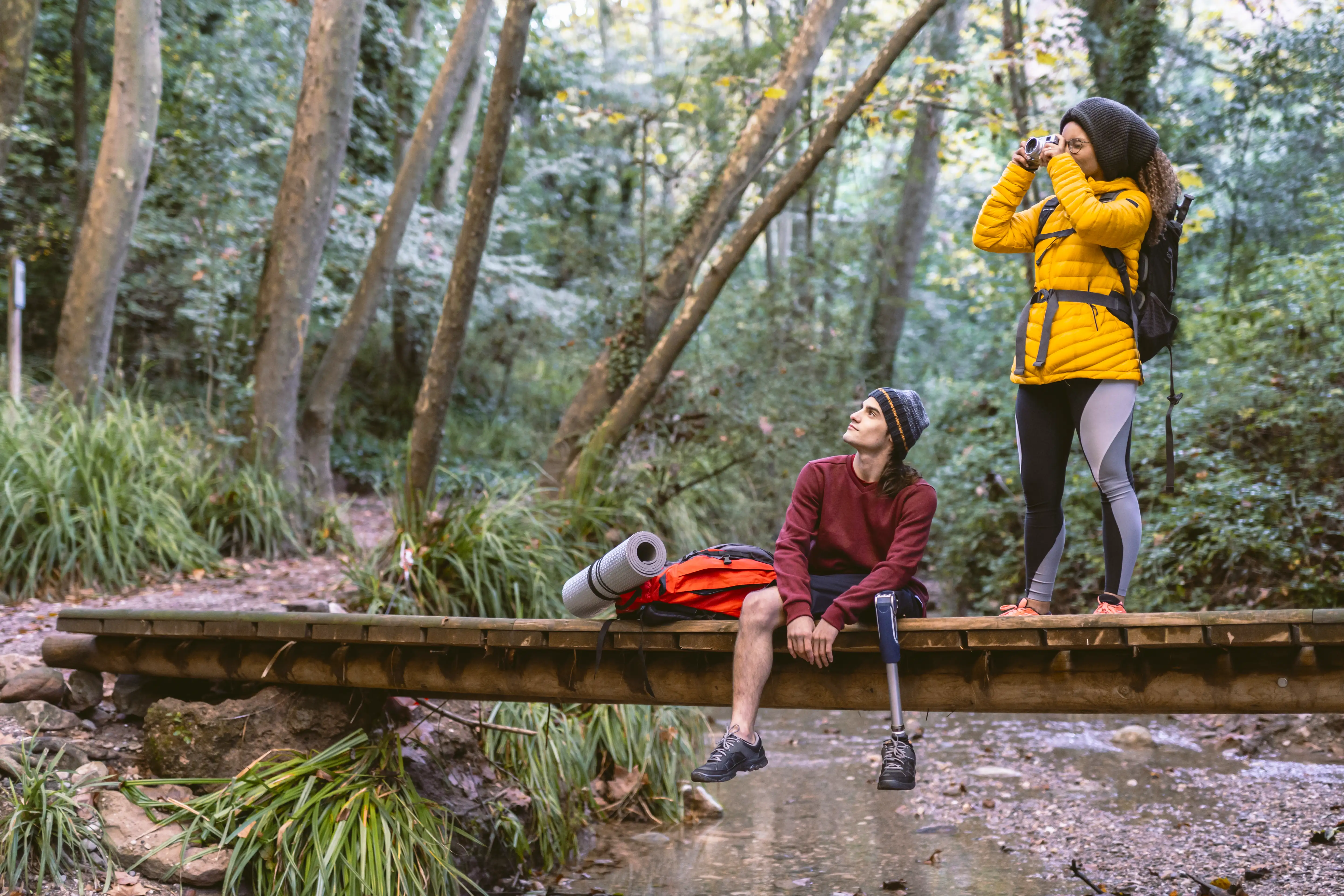Backpacker couple taking photos with a camera hiking in a forest.