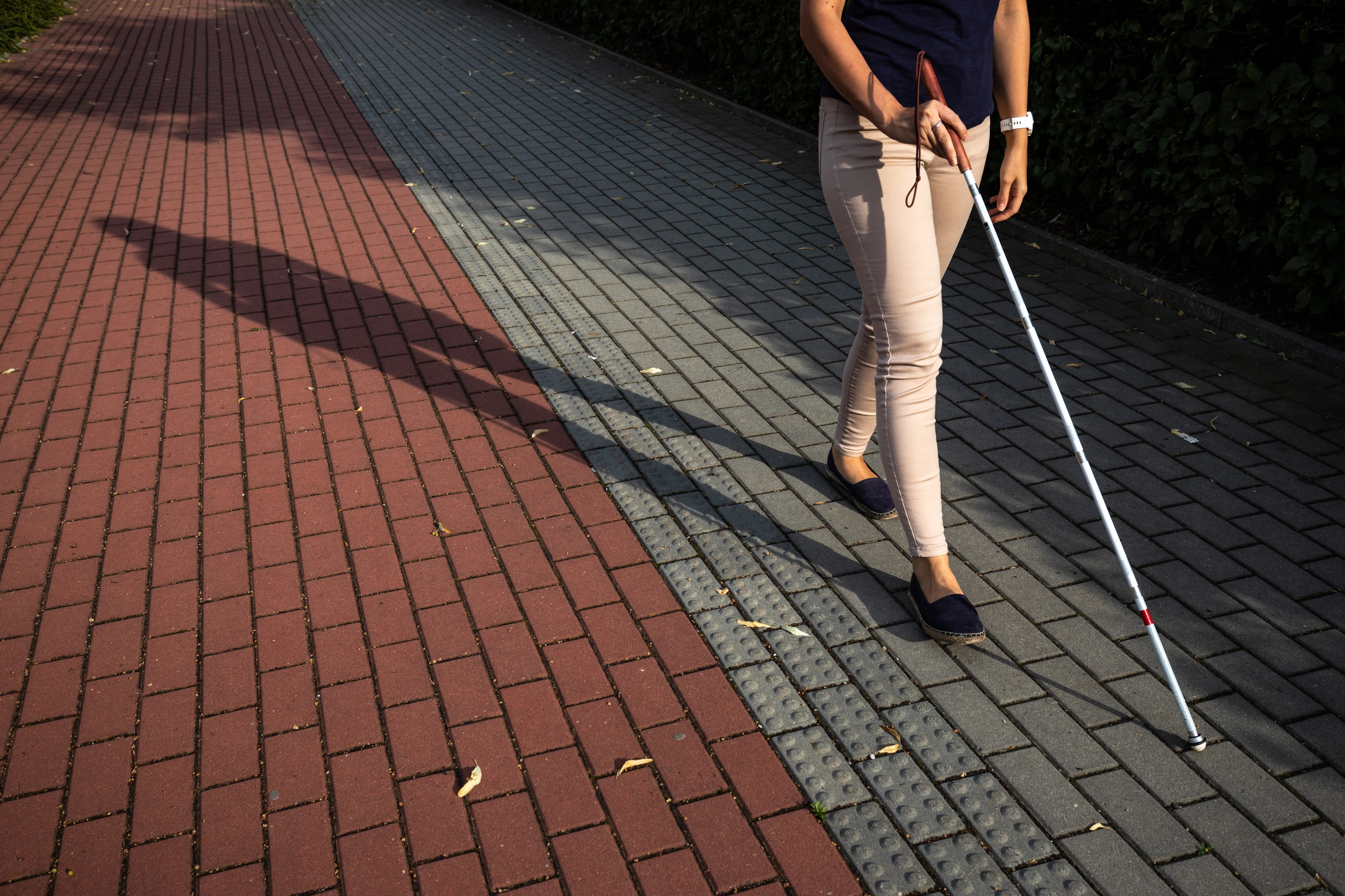 Visually impaired woman walking on city streets using her white cane