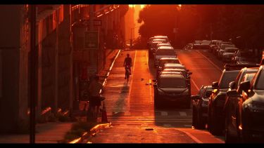 A busy city street glowing red in sunset heat