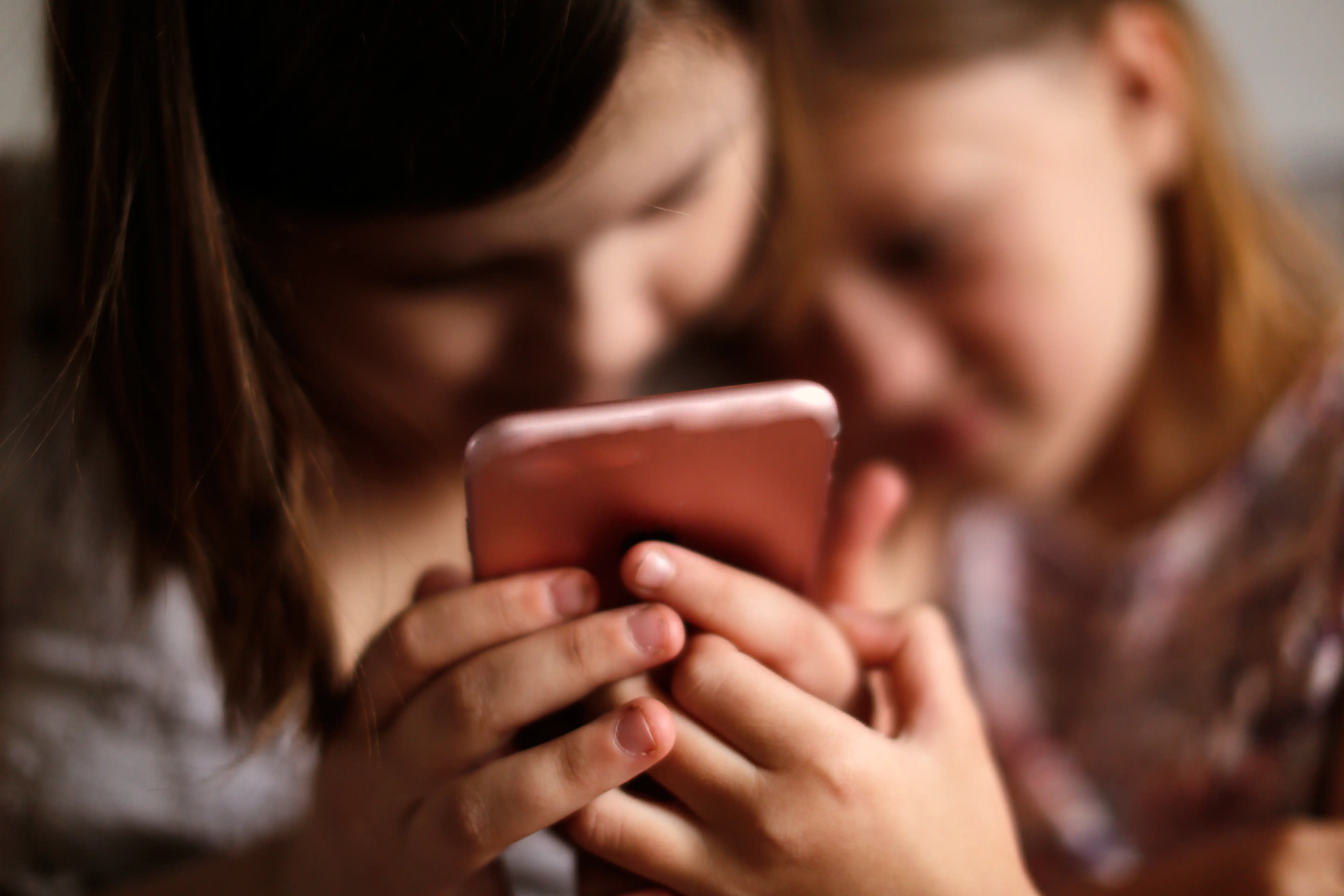 Two young teen girls looking at a mobile phone