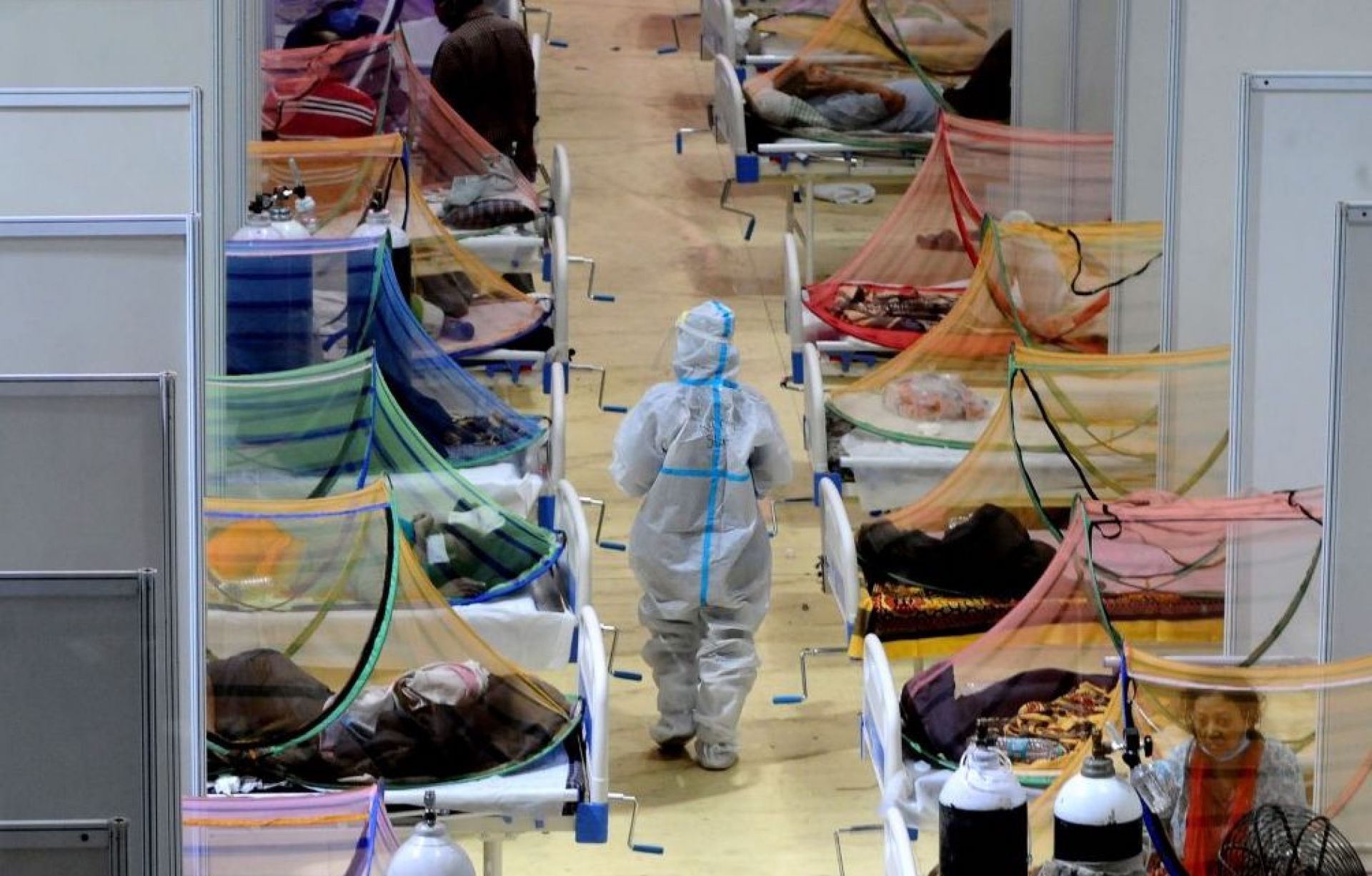 A health worker in full protective gear walks through a makeshift ward